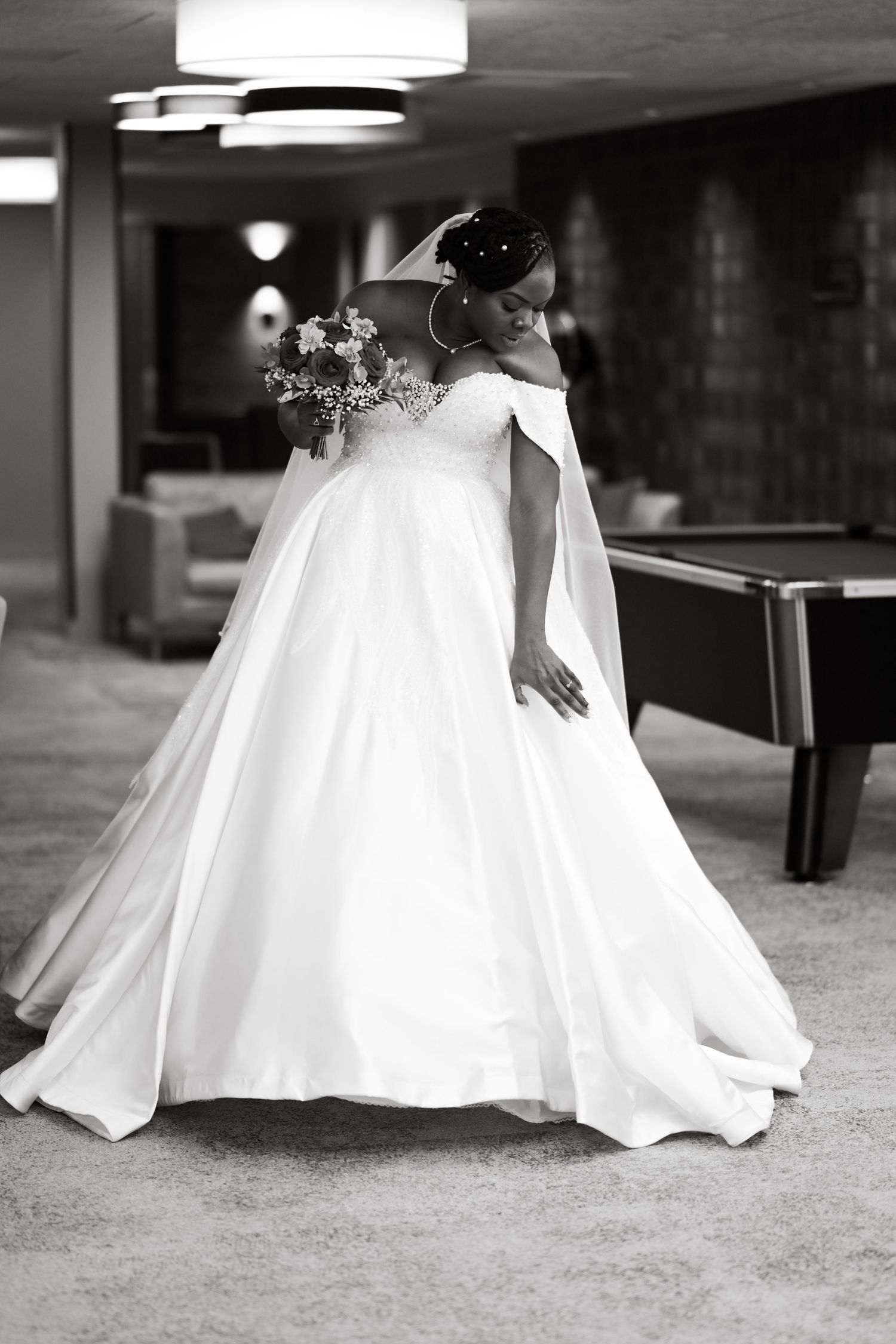 Elegant bride in a white ball gown twirls in a dramatic black and white photo.