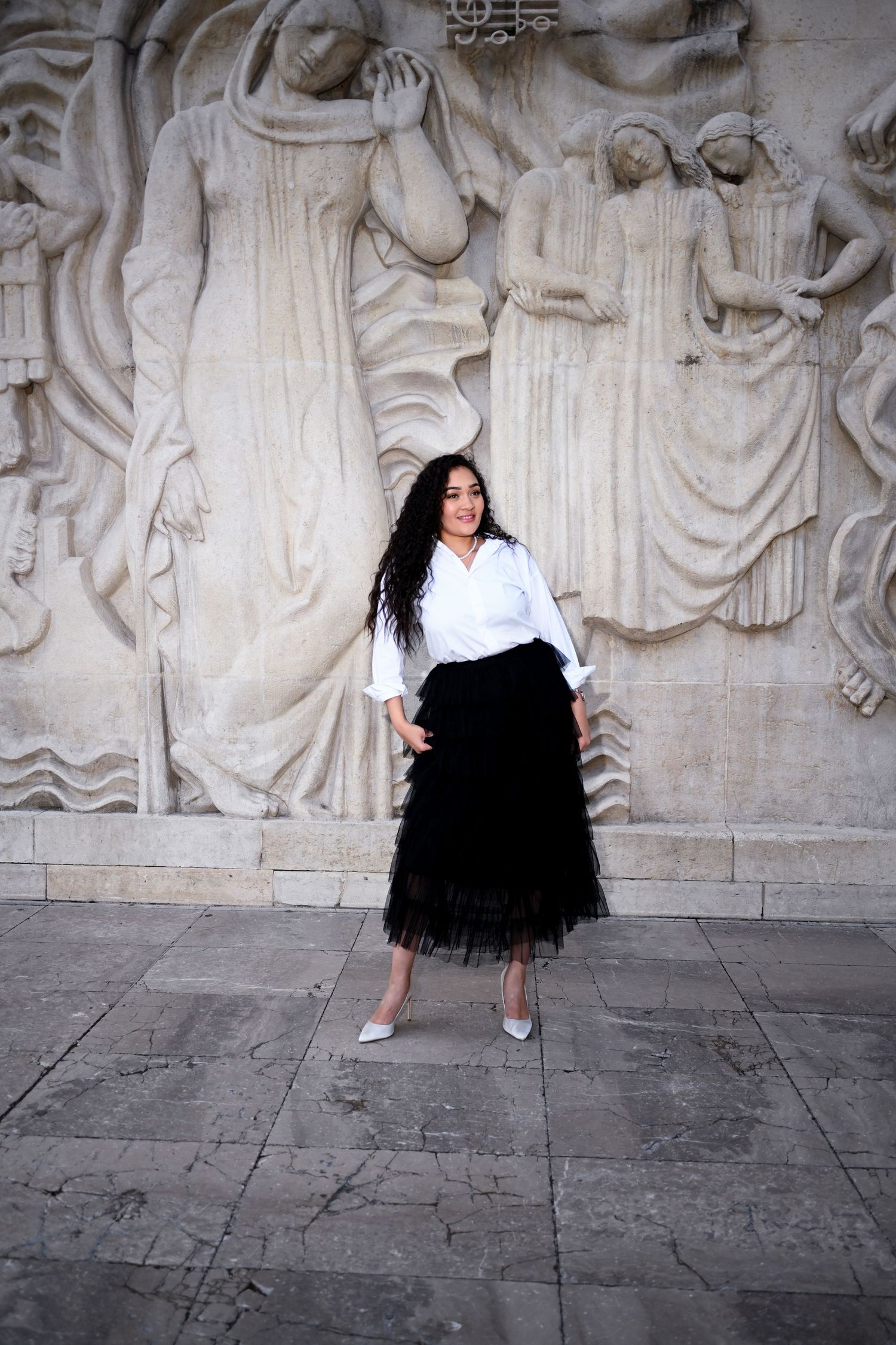 Striking contrast of modern fashion against classical stone relief wall sculpture.