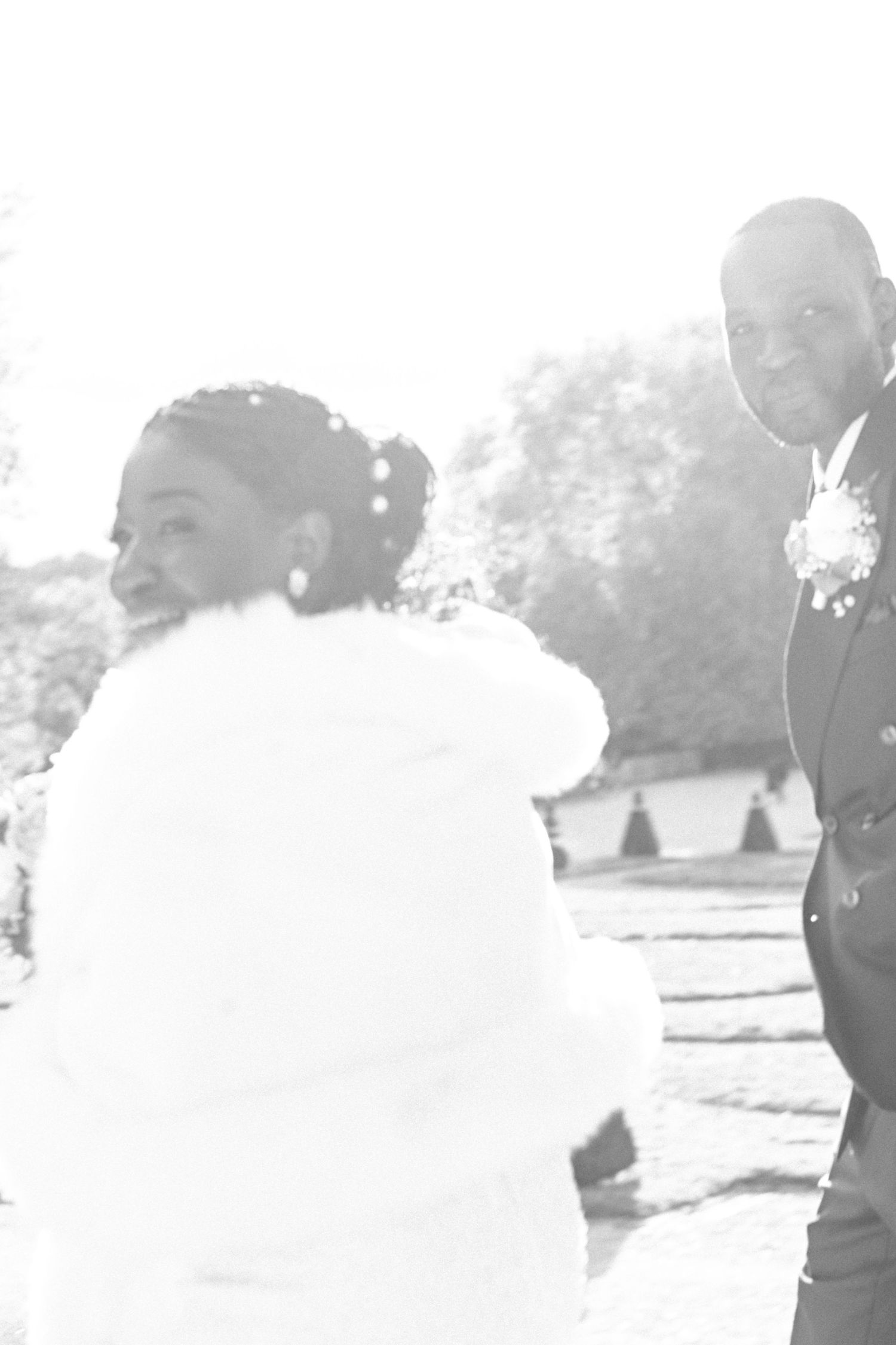 High-key wedding portrait capturing intimate moment between couple in garden setting.