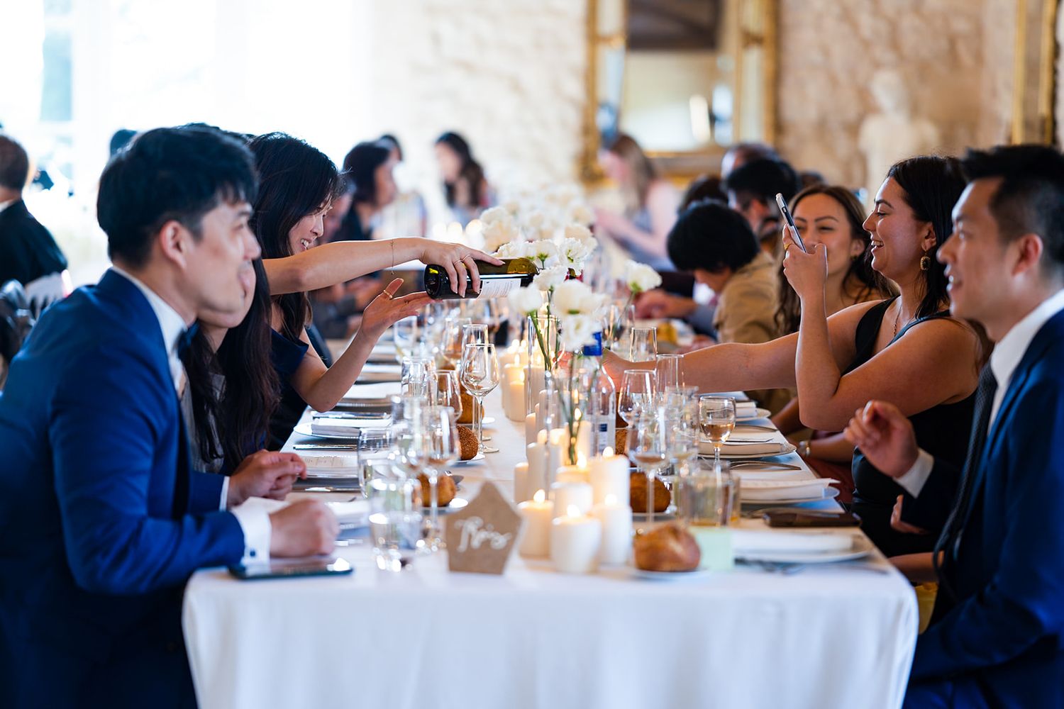 Wedding guests dine at elegantly set tables under crystal chandeliers.