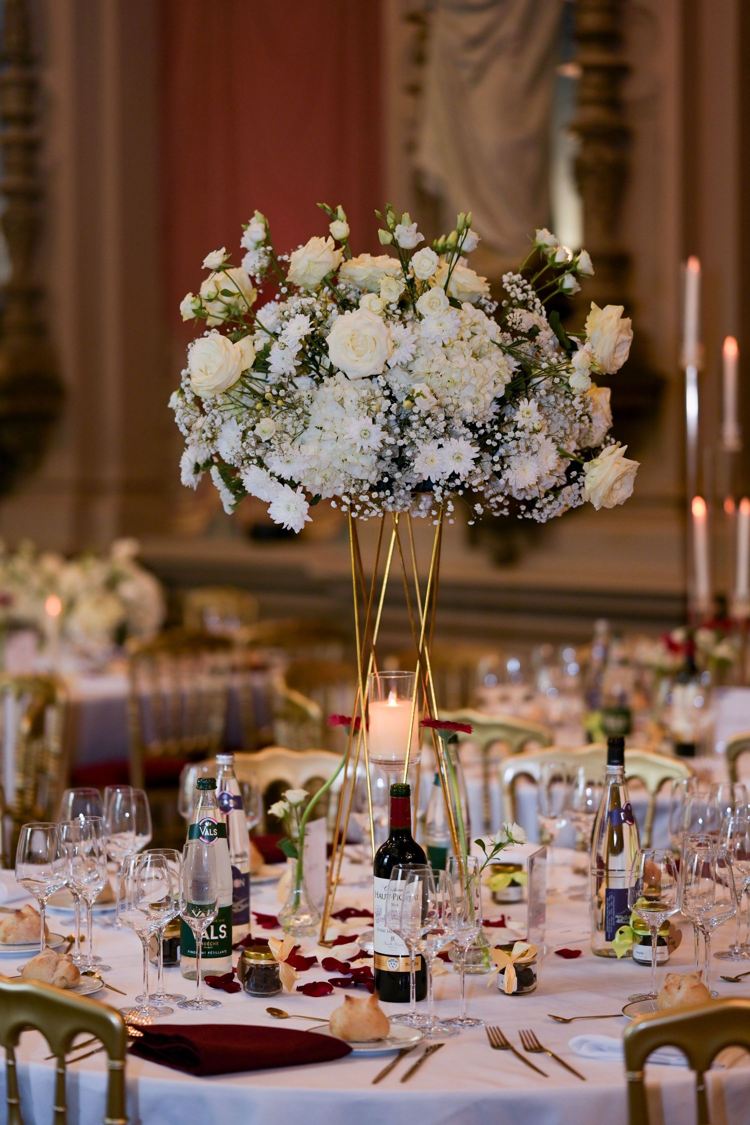 Elegant white floral centerpiece with roses and hydrangeas on formal wedding reception table.