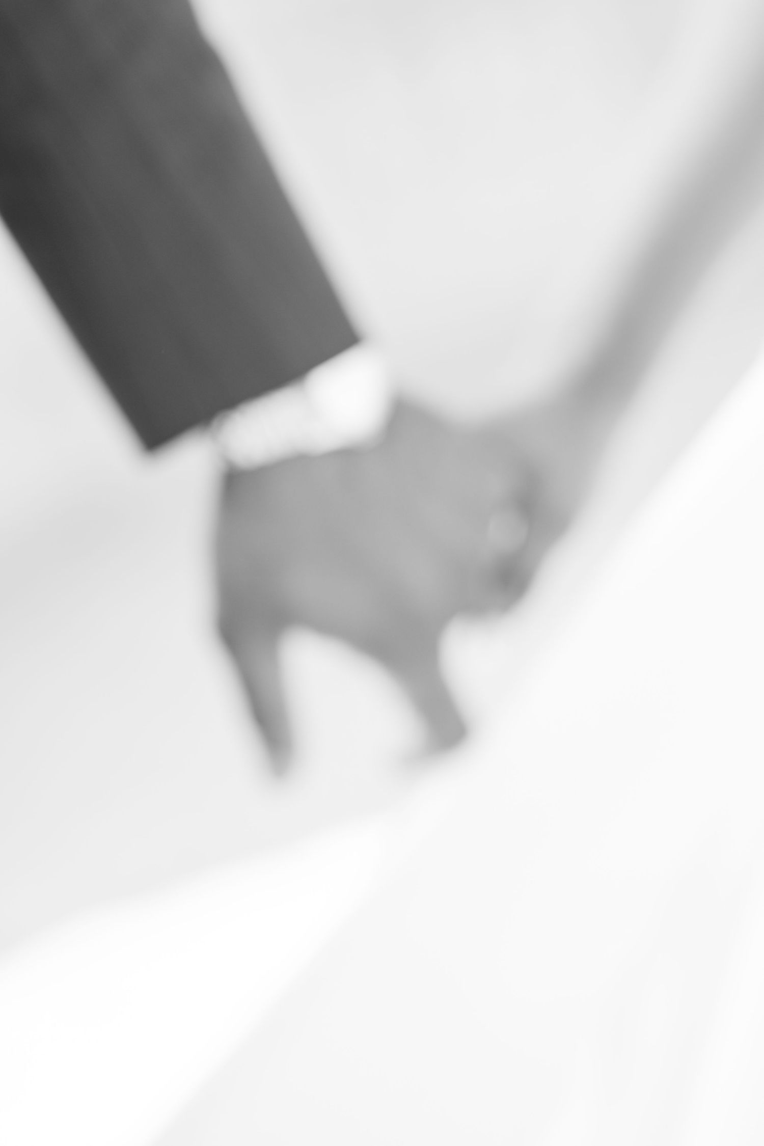 Black and white image of a couple holding hands on their wedding day.