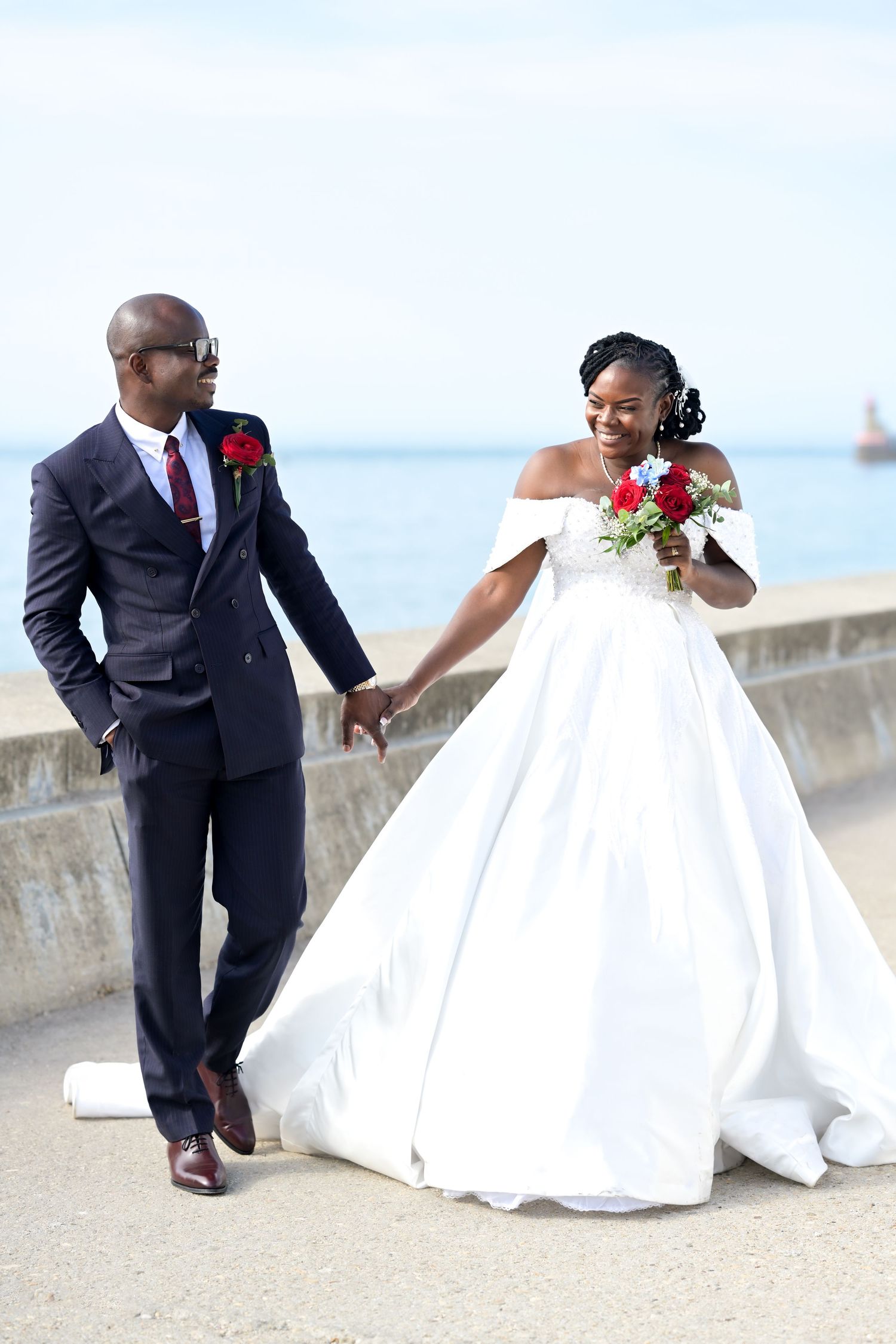 A bride and groom share playful moments on their wedding day by the ocean.