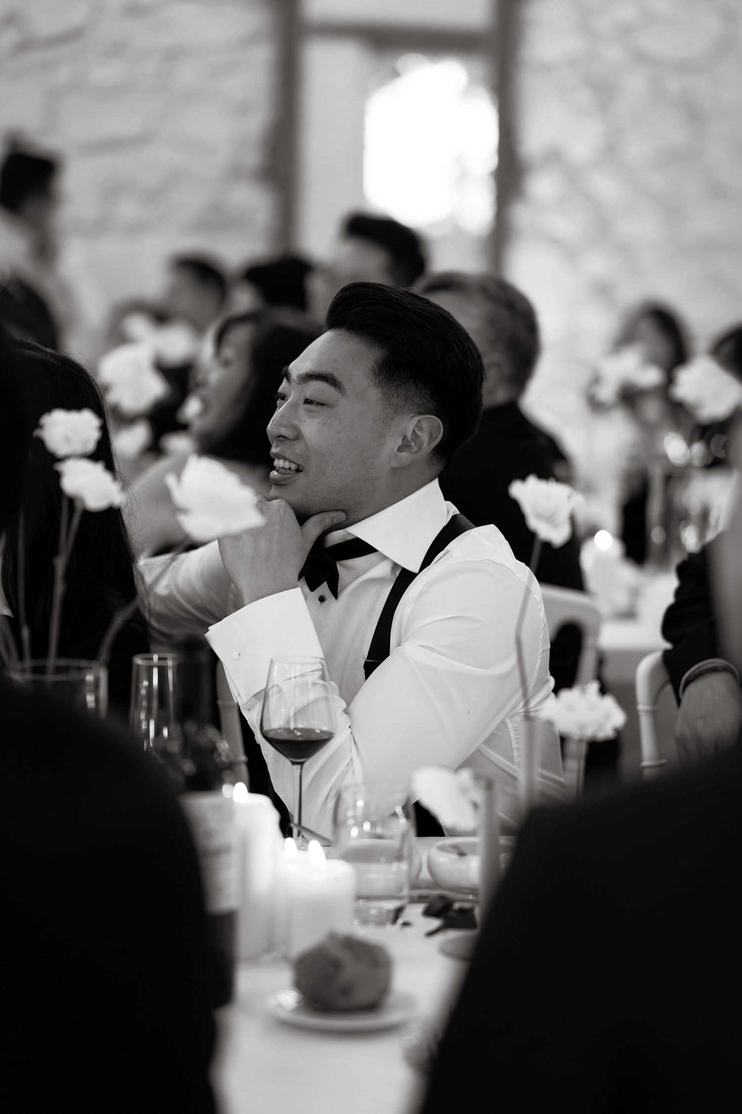 Guest in formal attire laughing during an elegant black and white reception.