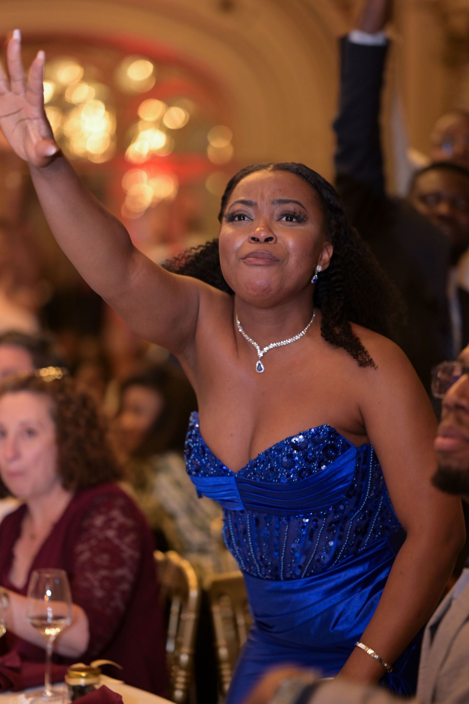 Guest in sparkling blue gown celebrating at formal event.