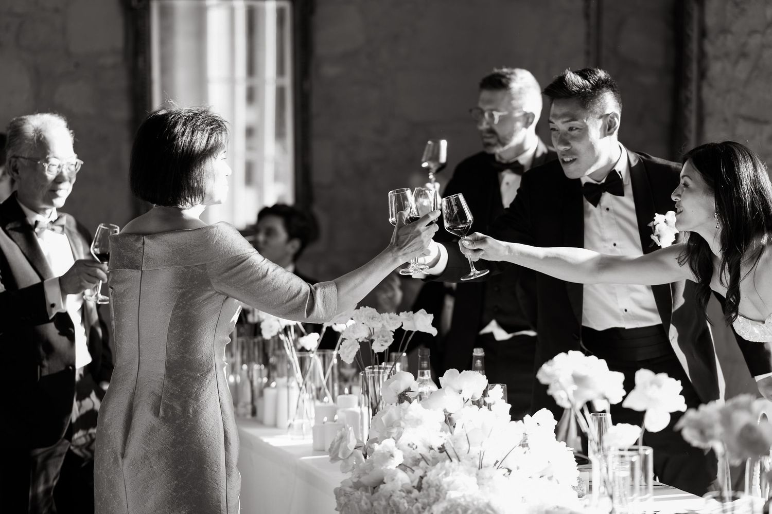 Wedding guests toasting with champagne glasses at an elegant reception dinner table.
