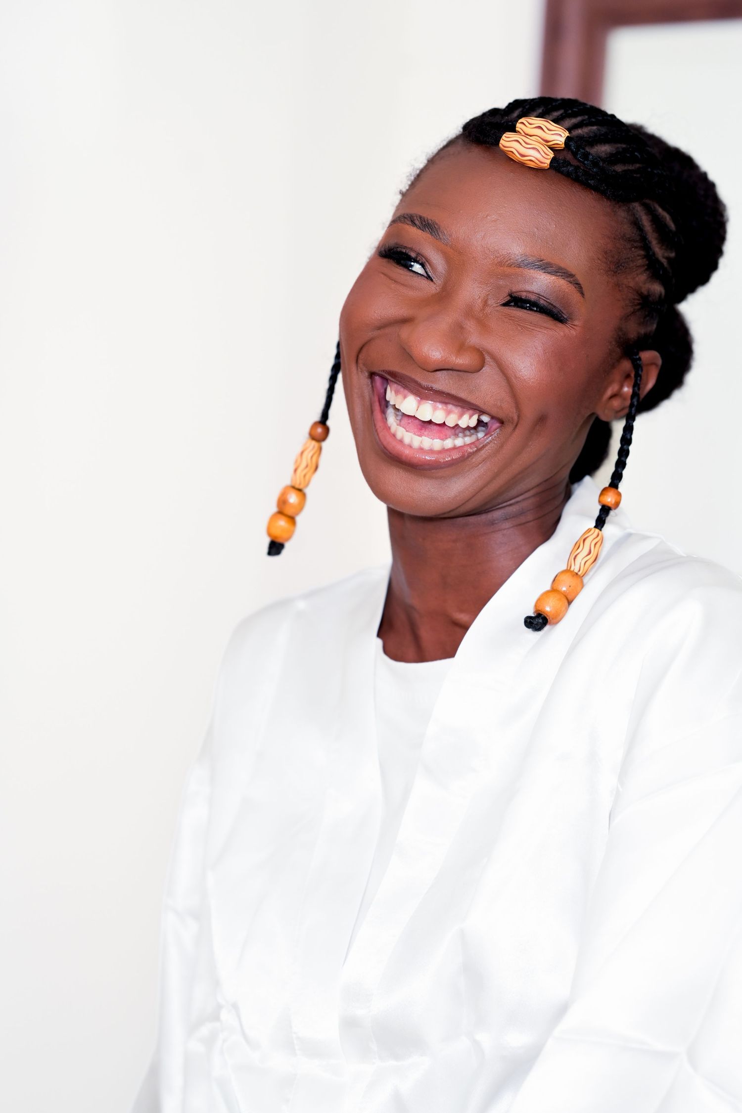 Four sequential photos showing someone wearing white clothing and orange earrings with a bright joyful expression.