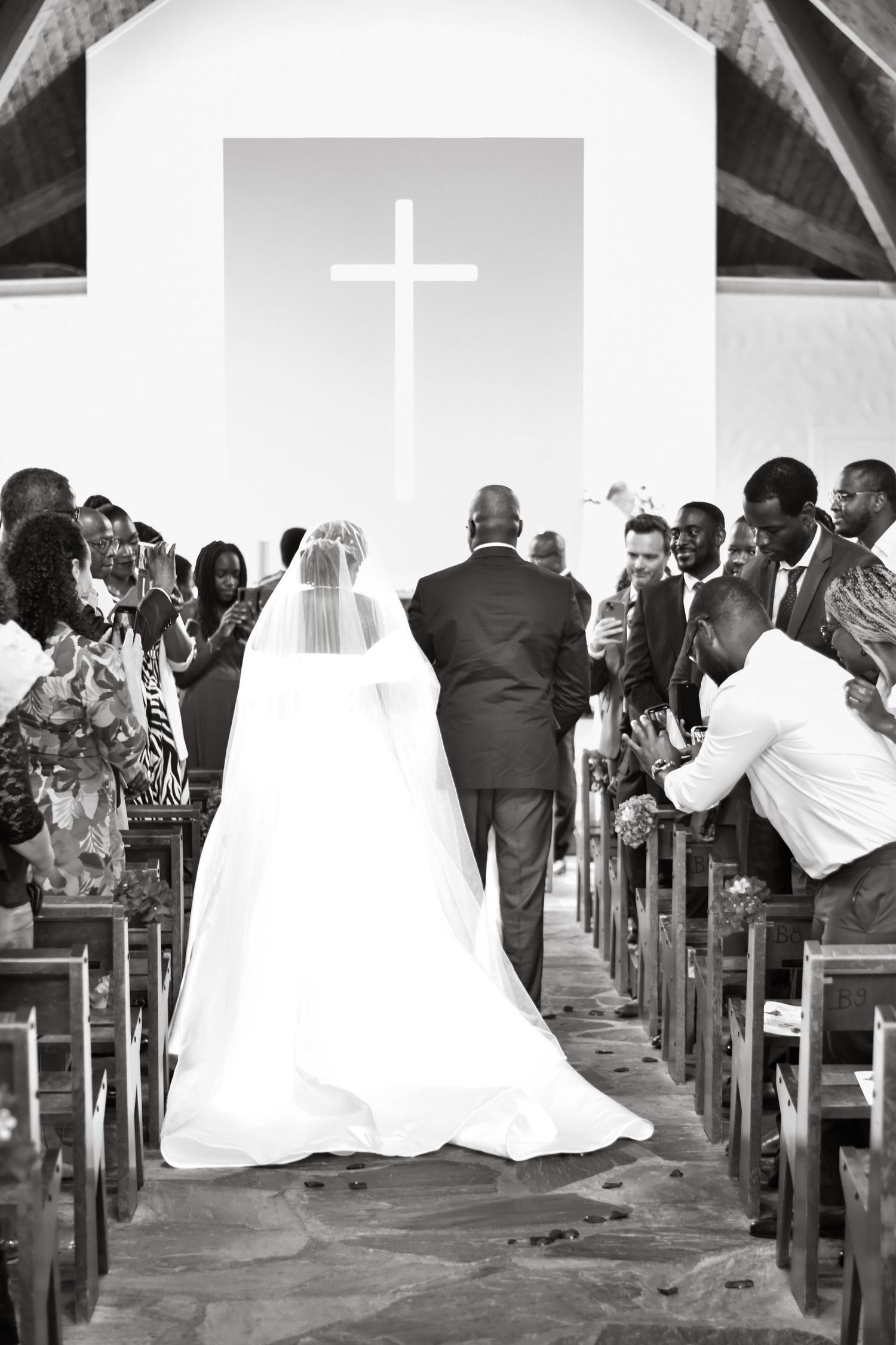 Wedding ceremony in progress inside church with guests seated in wooden pews.