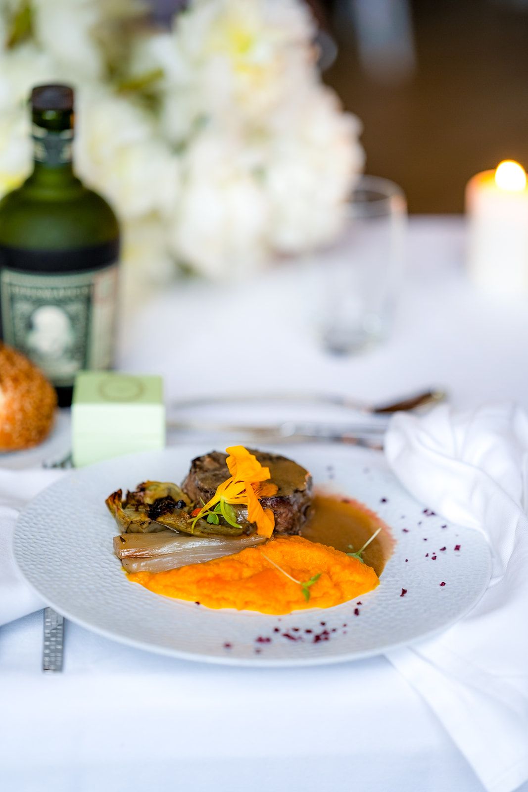 Gourmet plated dish with orange sauce and garnish served at formal event.