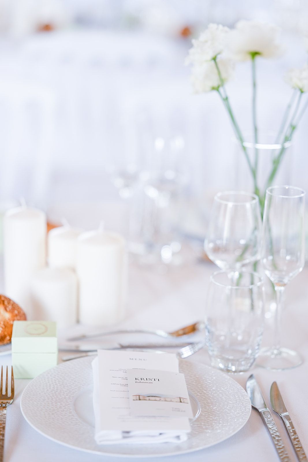 Elegant white table setting with delicate flowers and glassware for a formal event.
