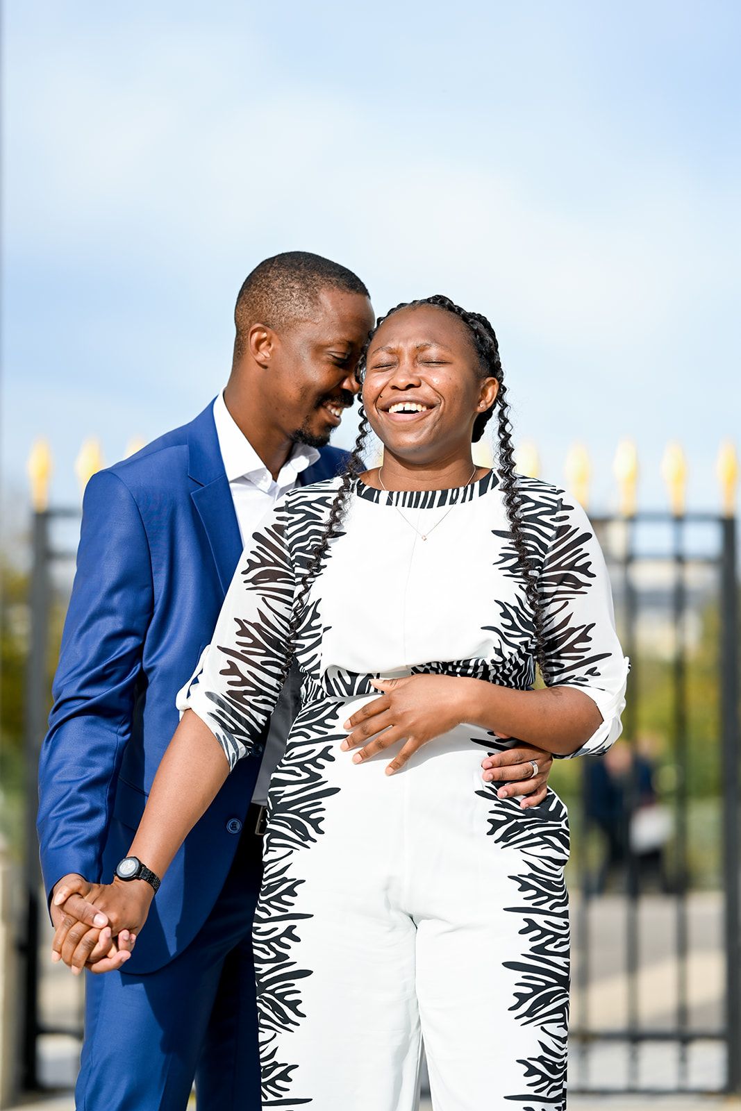 A joyful couple sharing an intimate moment outdoors wearing blue and white outfits.