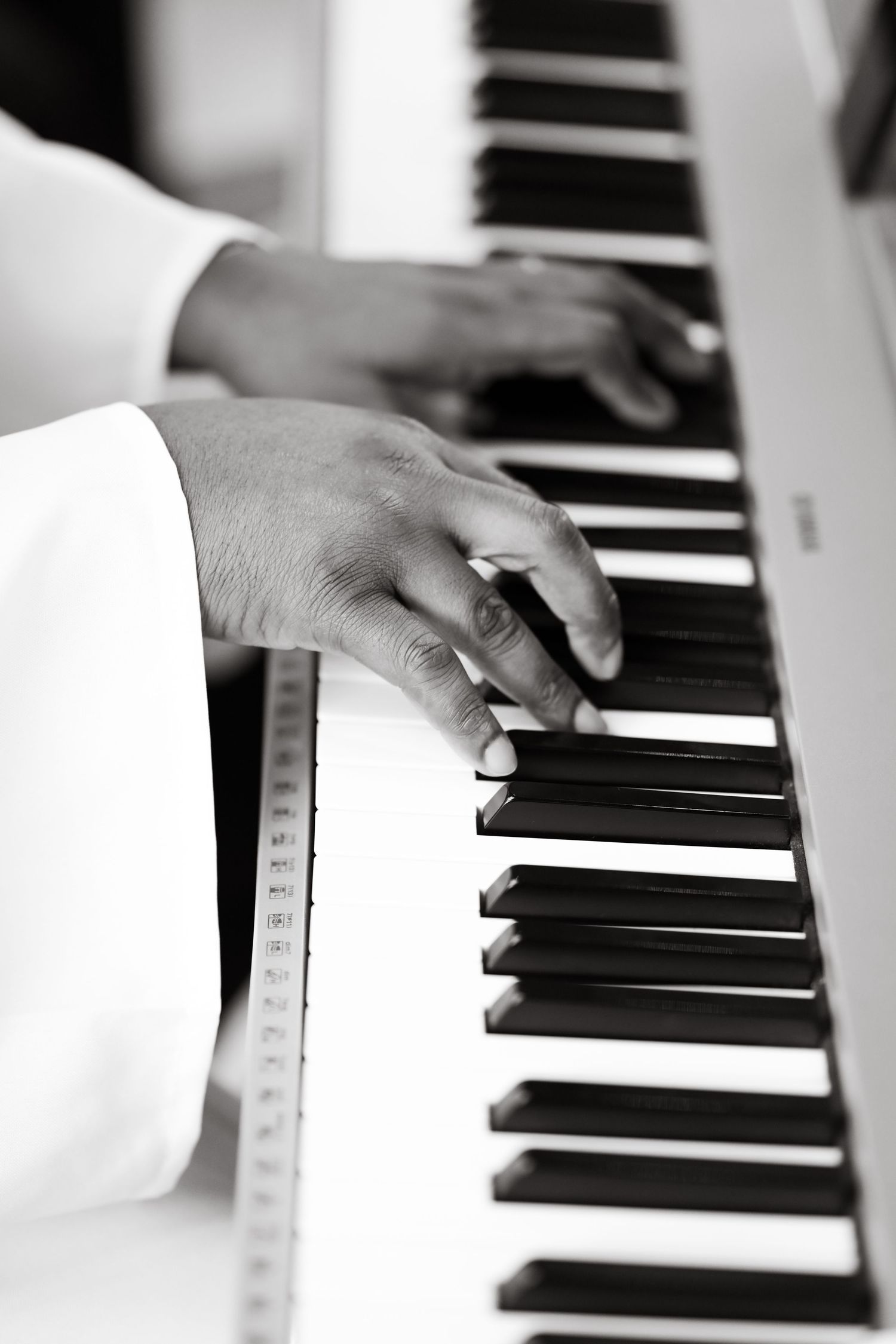 Black and white close-up of hands playing piano keys.