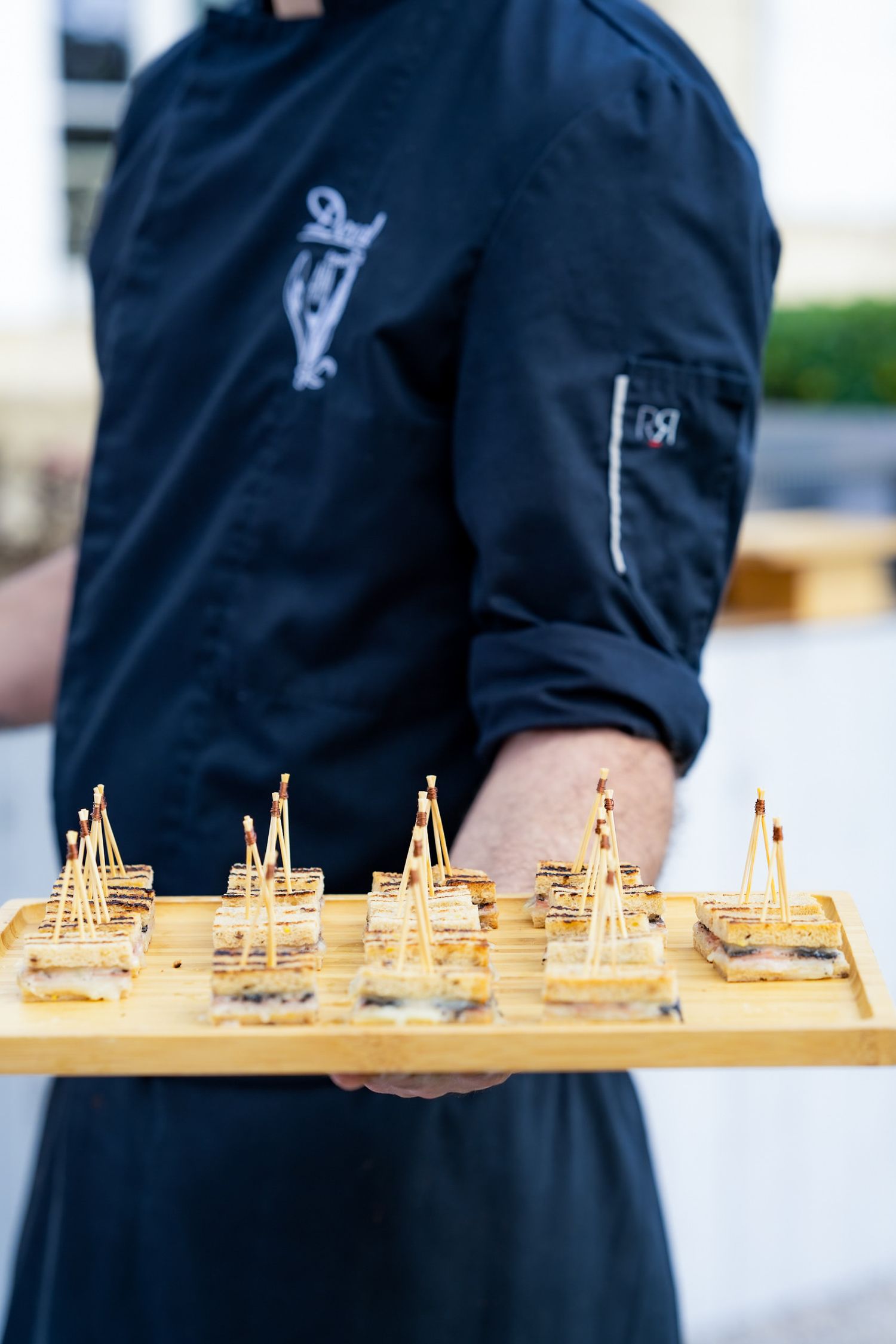A server in uniform presents golden appetizer displays on a decorative tray.