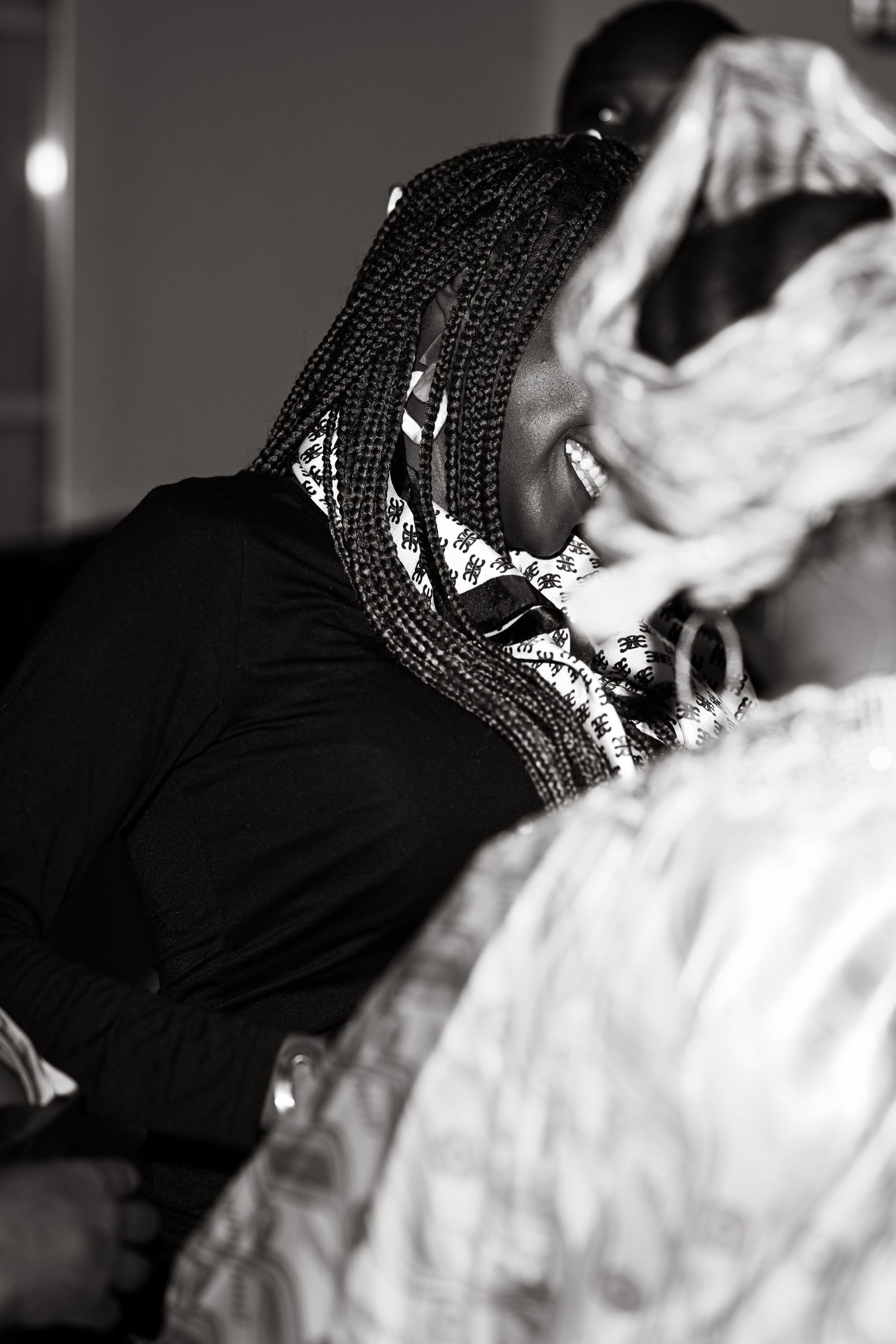 A black and white photo showing a person with braided hair in a dark outfit.