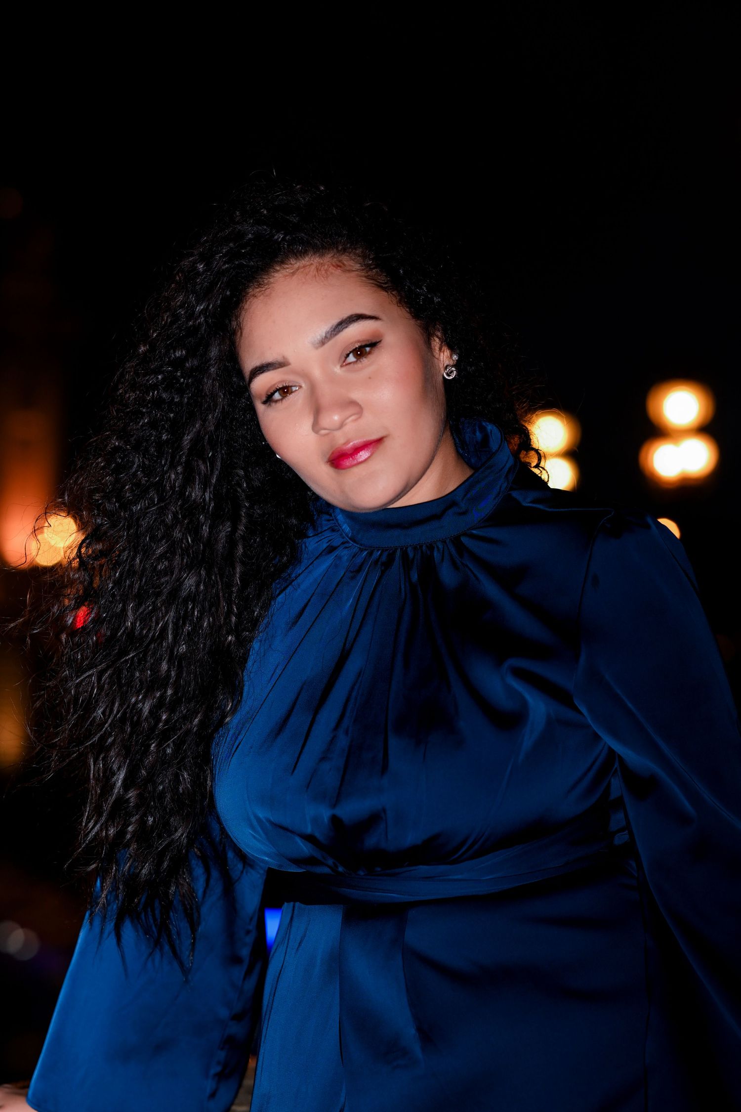 Artistic portrait in blue featuring curly hair and dramatic lighting against a dark background.