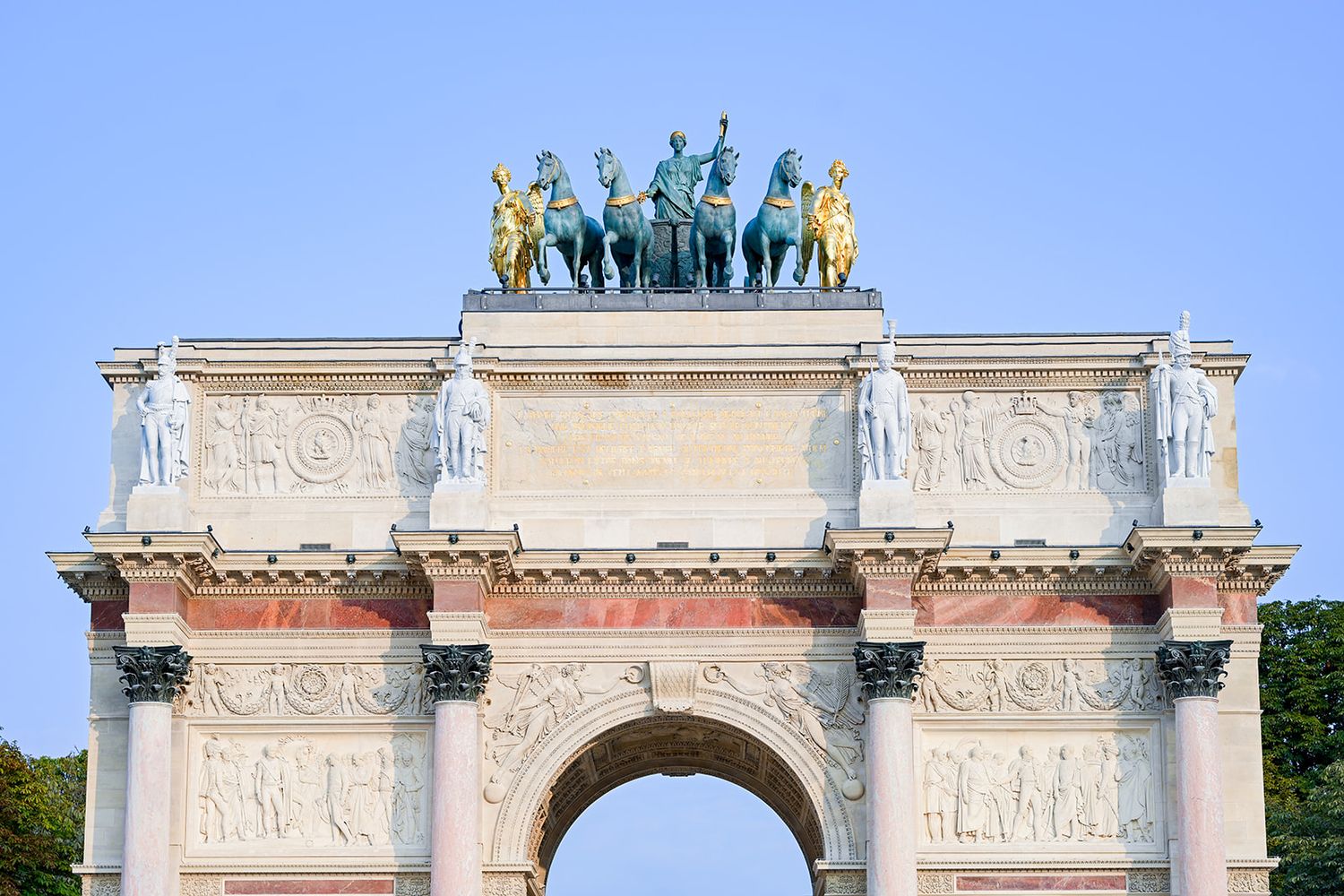 Ornate classical architecture with decorative stone arches and statues adorning the top of a historic building.