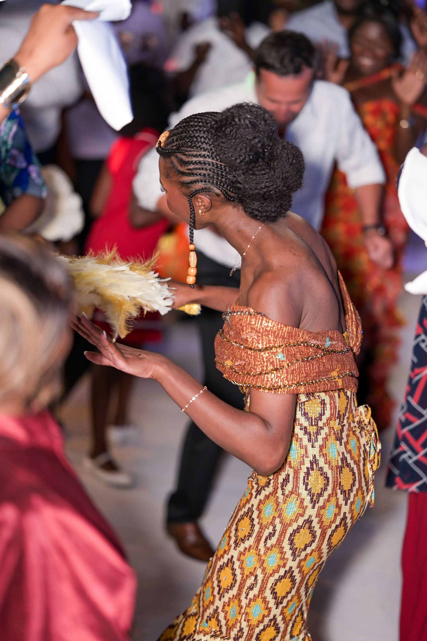 Dancer in traditional African print dress performing energetic moves at celebration.