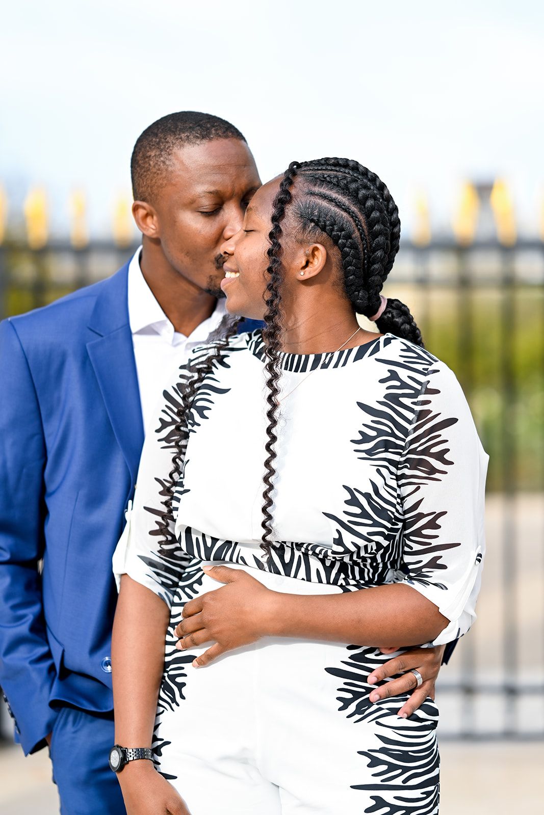 A romantic couple embrace while wearing contrasting blue and zebra print outfits.