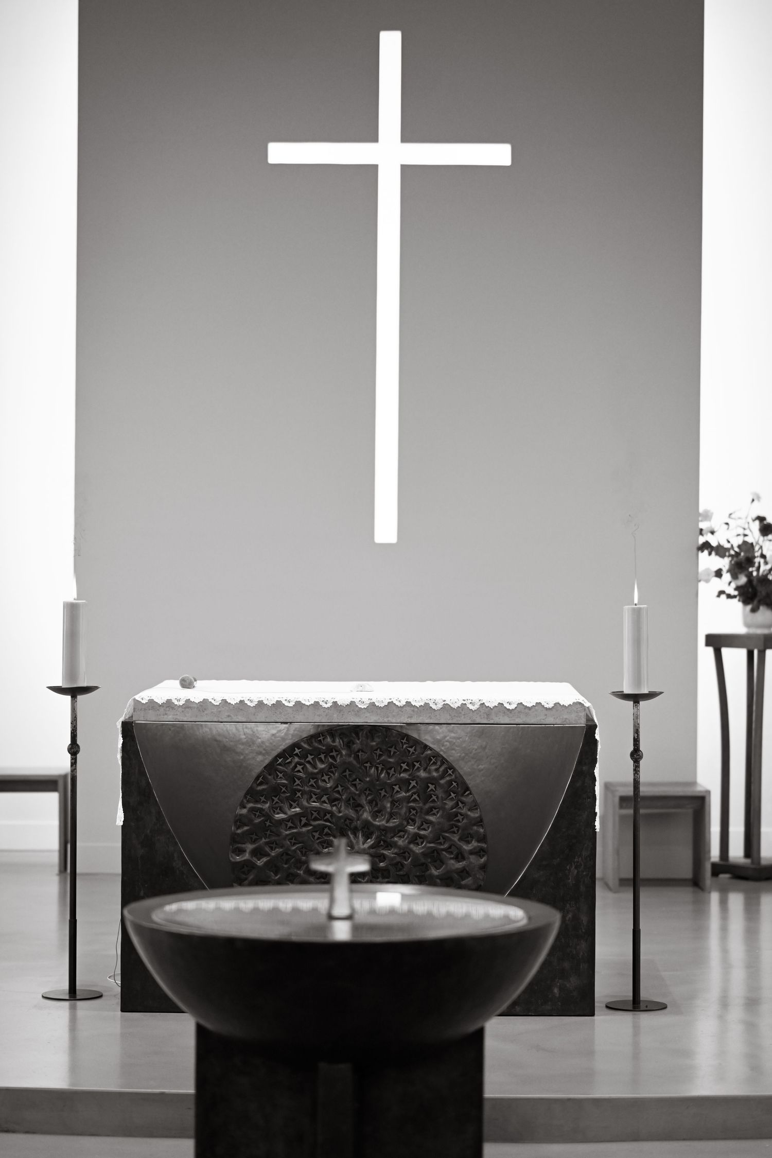 Modern church altar with white cross and candles arranged in minimalist style.
