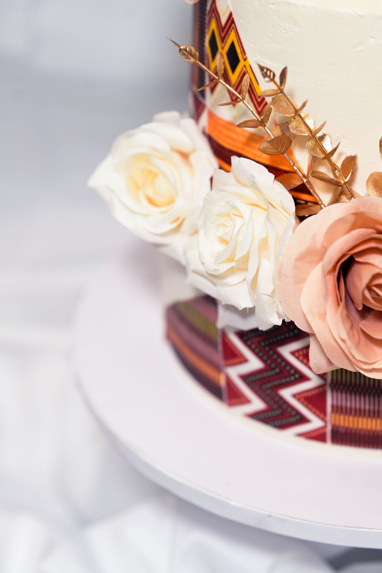 Close-up of wedding cake details showing peach roses and burgundy geometric patterns.