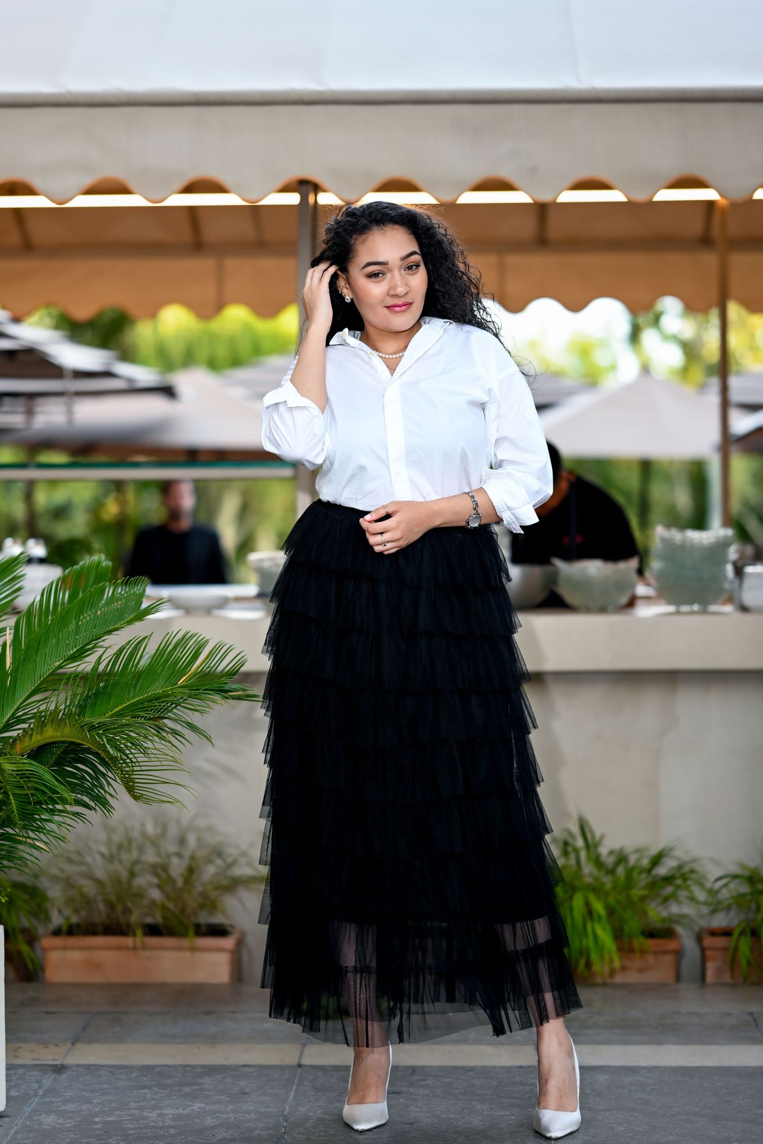 Chic outdoor fashion pose combining classic white shirt with dramatic black tulle skirt.
