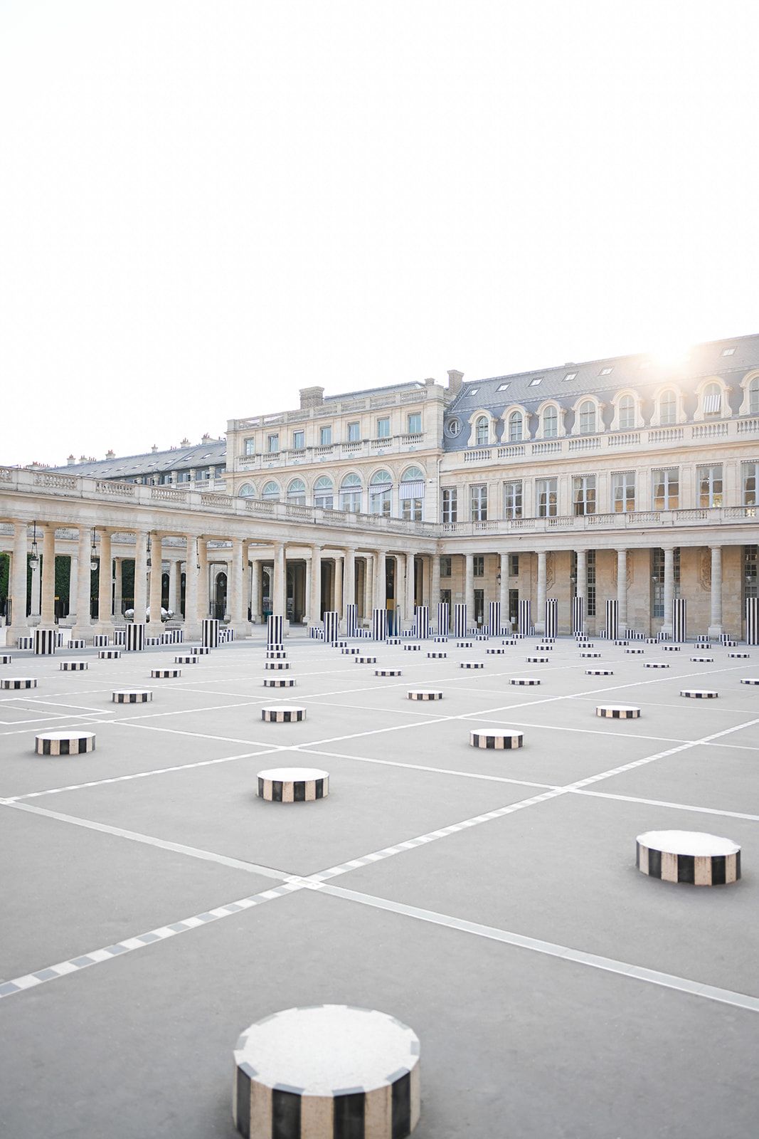 Elegant courtyard featuring geometric patterns of circular seating arrangements against historic building facade.