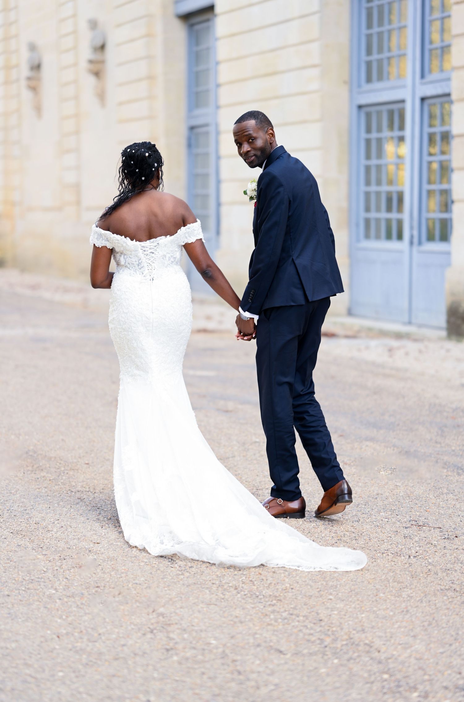 A romantic wedding photo showing a couple in formal attire on a cobblestone street.