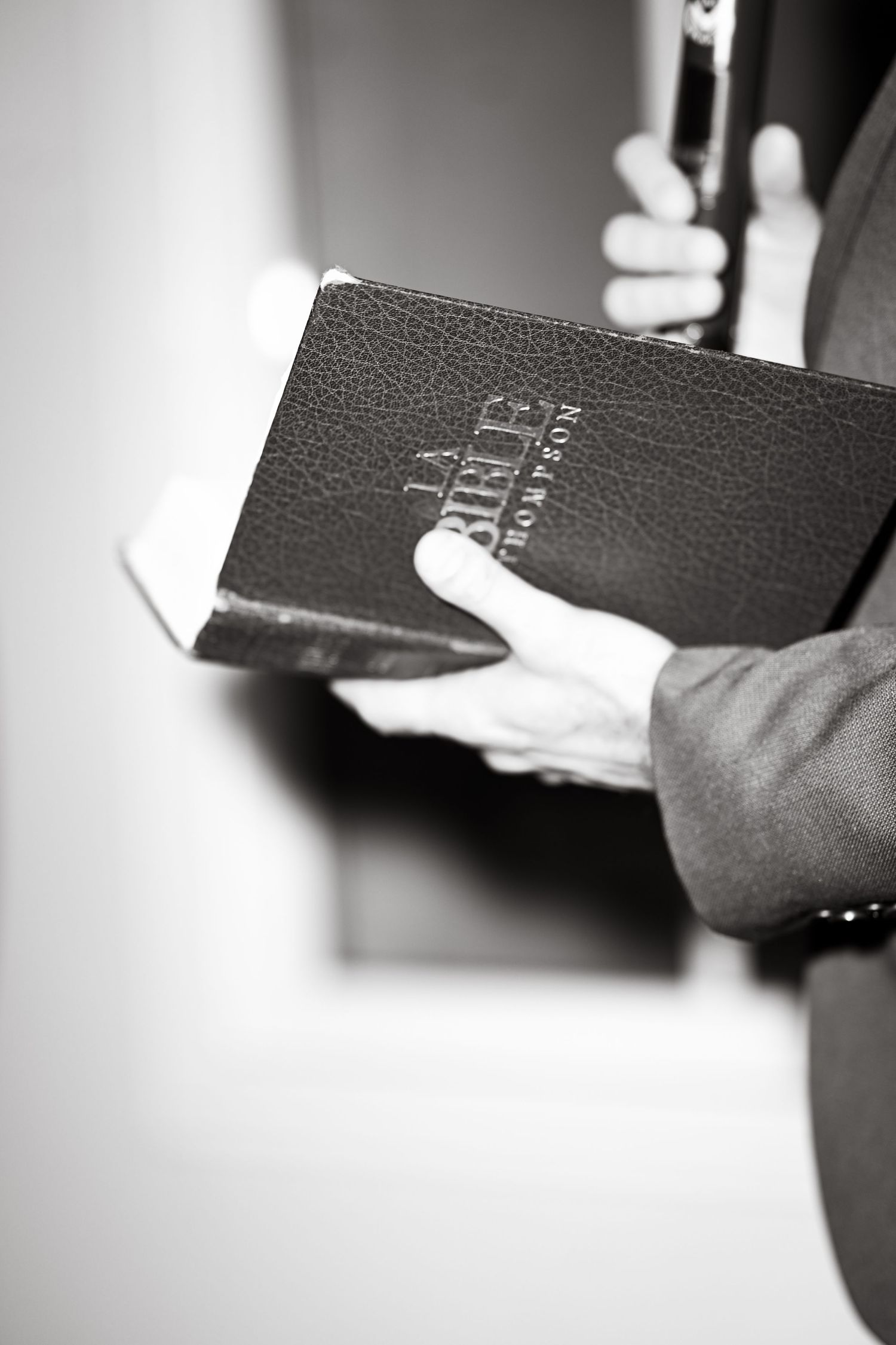 Black leather Bible being held in hands during a religious service.