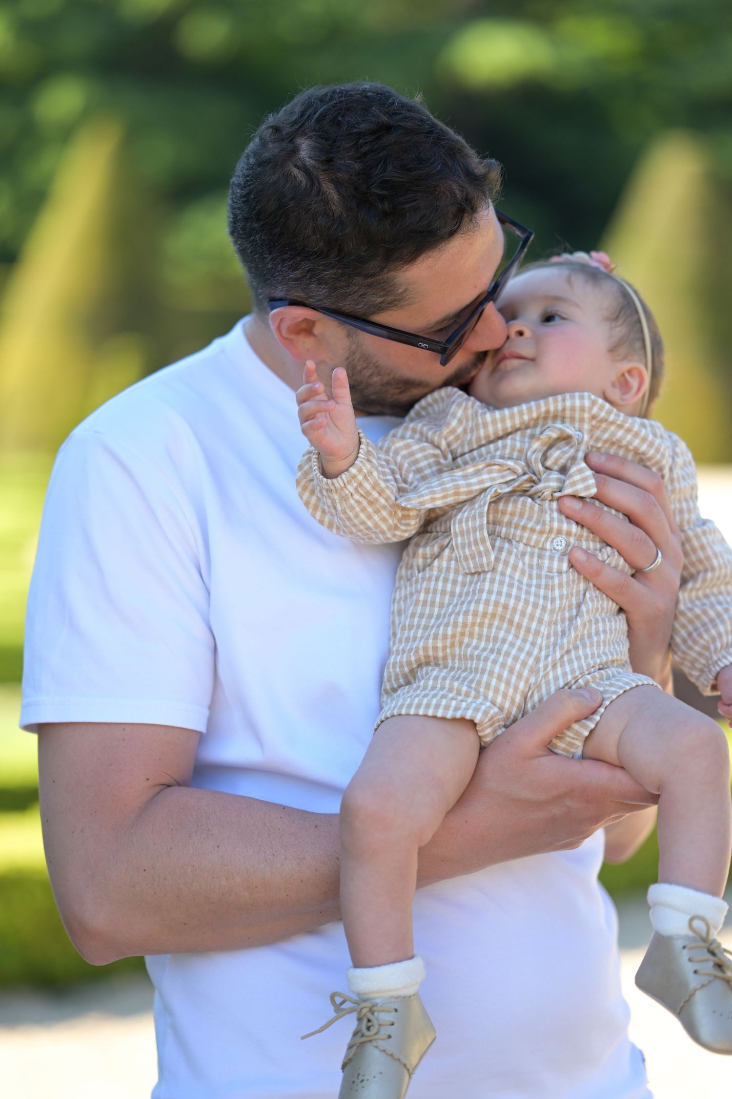 Sweet interaction between parent and baby in a sunny outdoor setting.