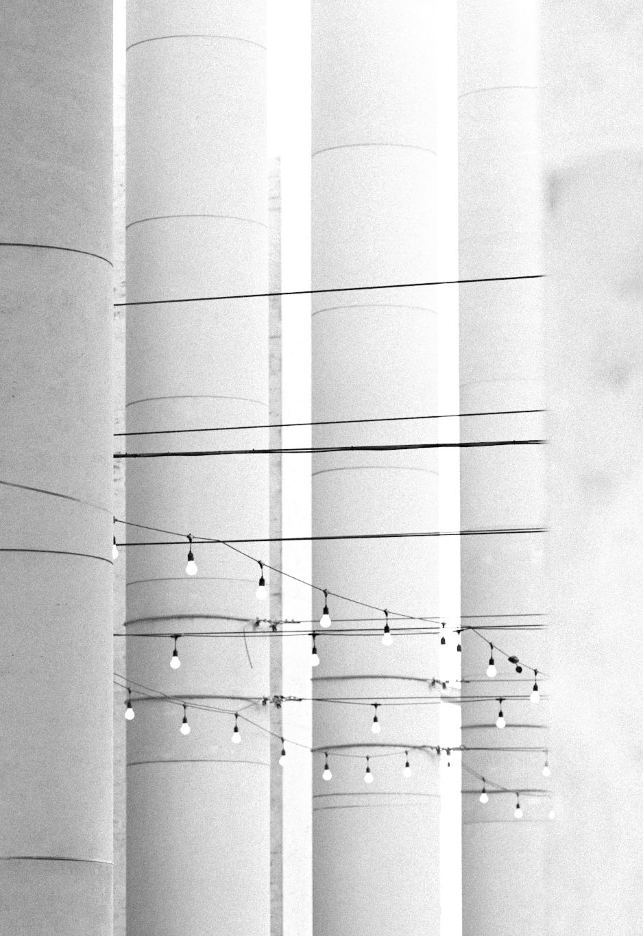 Minimalist architectural detail of white columns with hanging string lights creating geometric patterns.