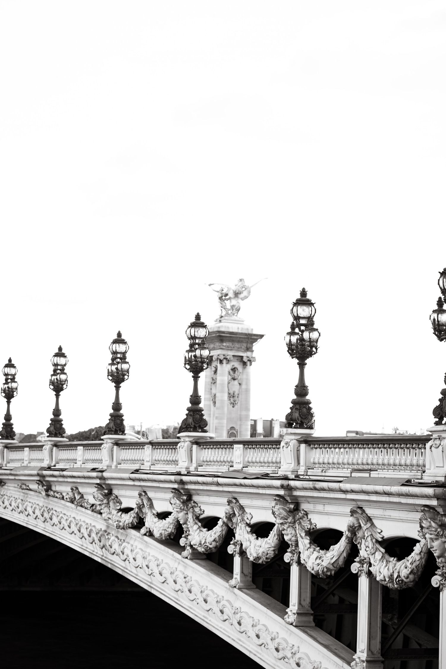 Ornate bridge railing with decorative lamp posts and columns in black and white.