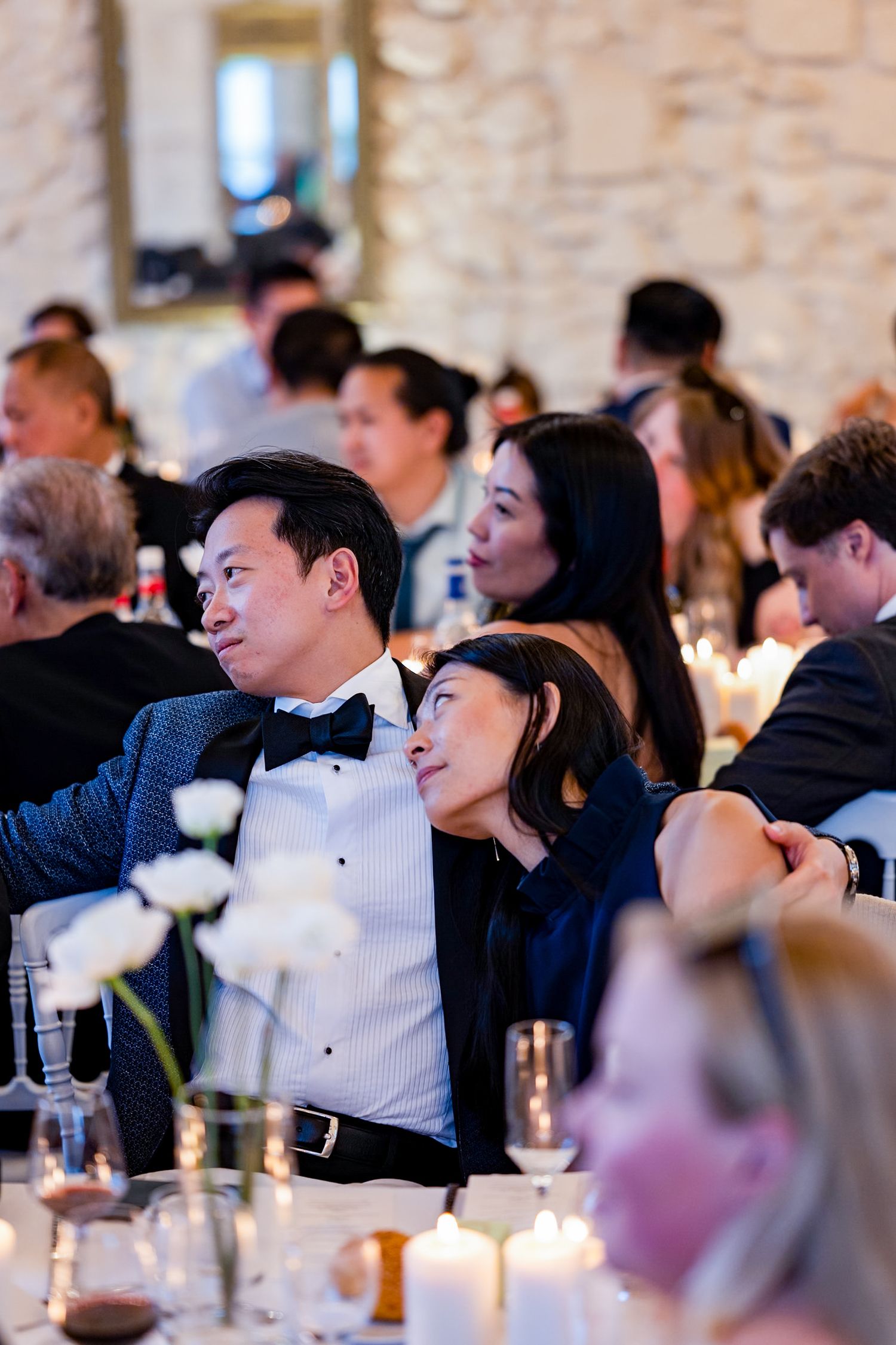 Guests enjoying an elegant wedding reception with candlelit tables and formal attire.