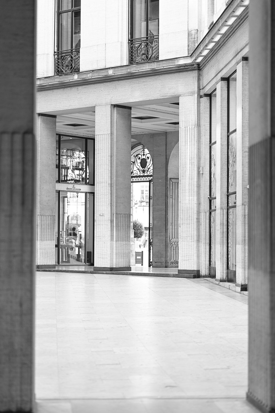 Black and white architectural photograph of a modern colonnade with glass windows and pillars.