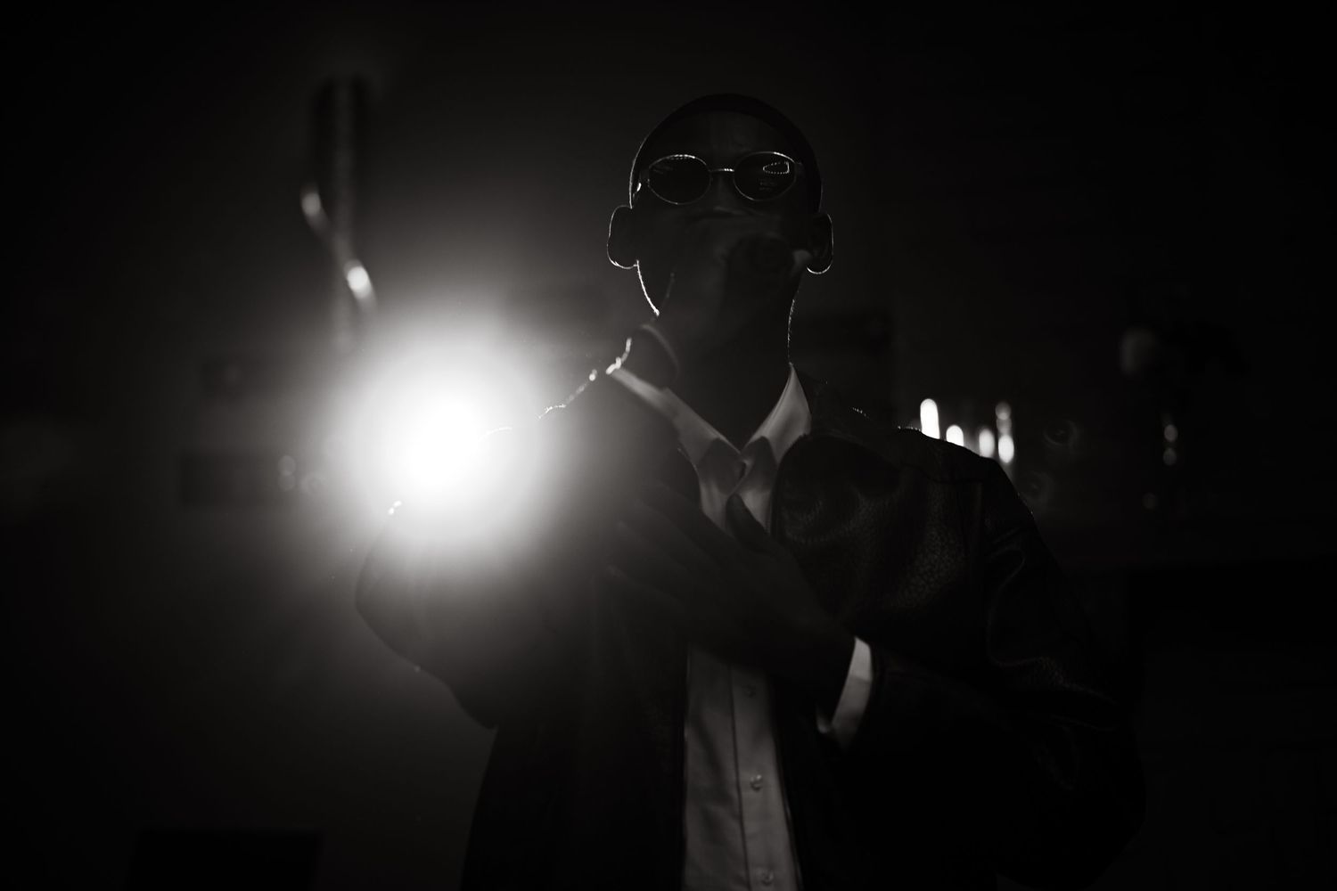 Dramatic silhouette of performer against bright stage light in dark setting.