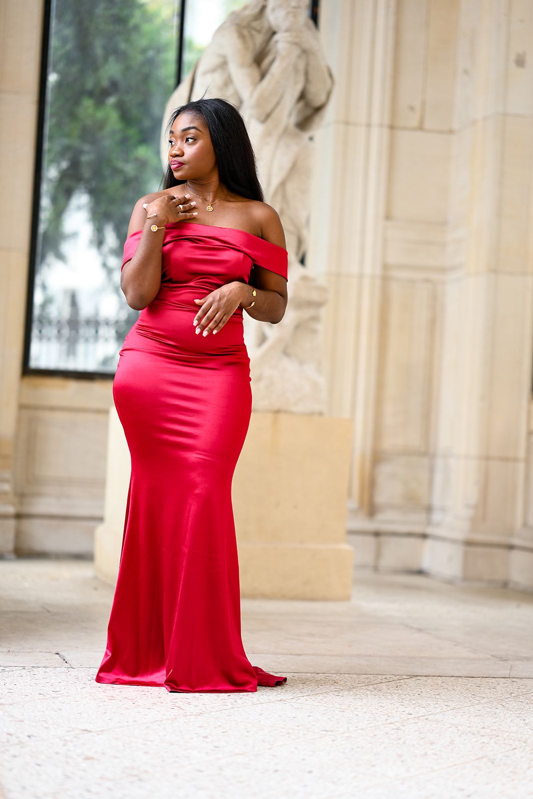 Glamorous red satin evening gown photographed against classical architectural backdrop.