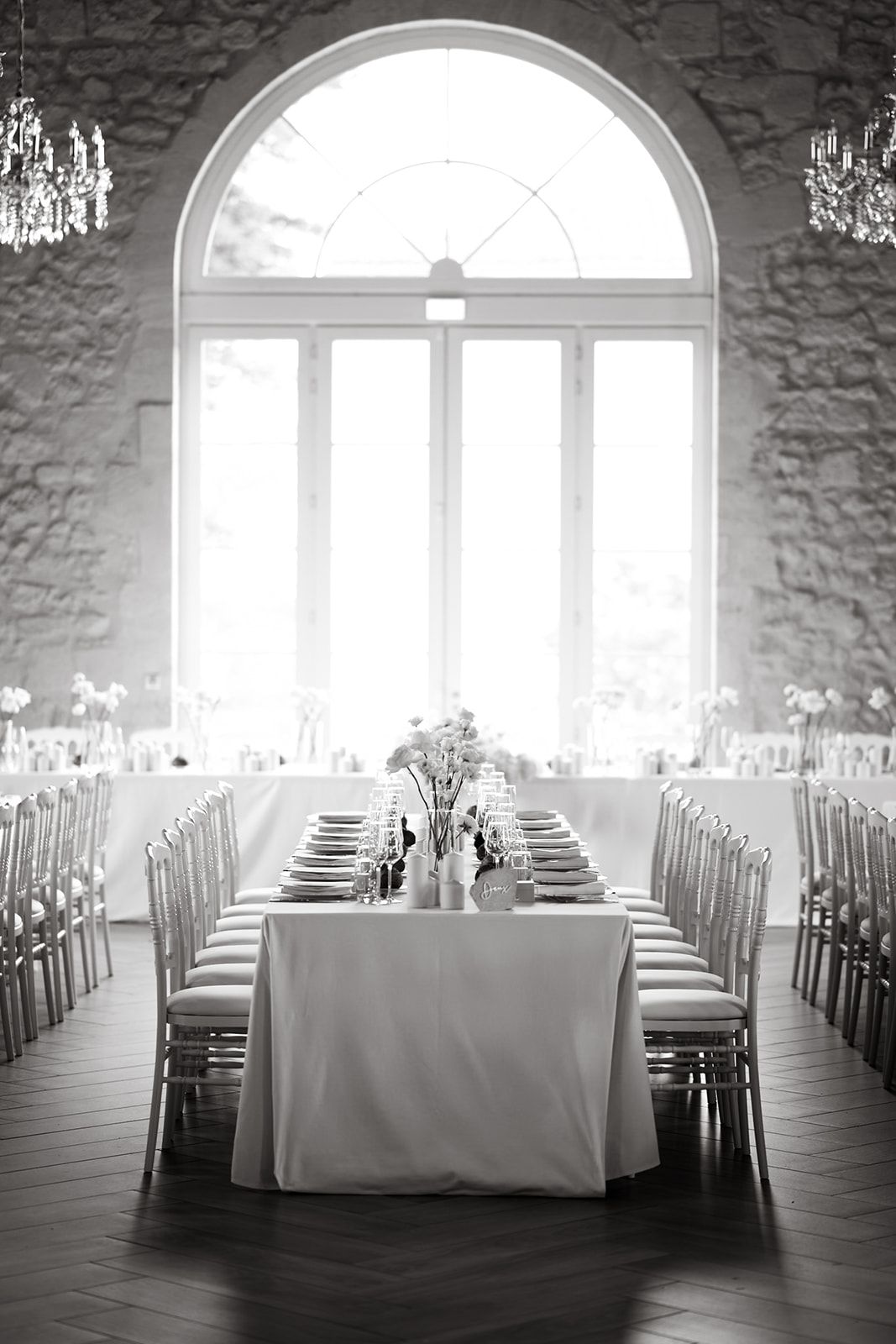 Elegant wedding reception hall with white tables and arched windows.