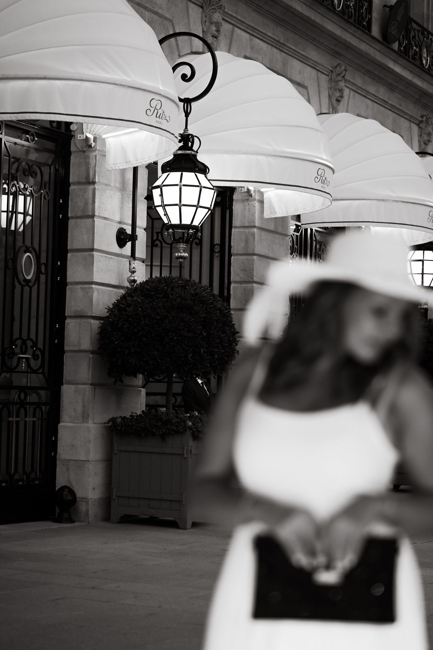 A row of elegant white archways with hanging lamps creates a classic architectural corridor.
