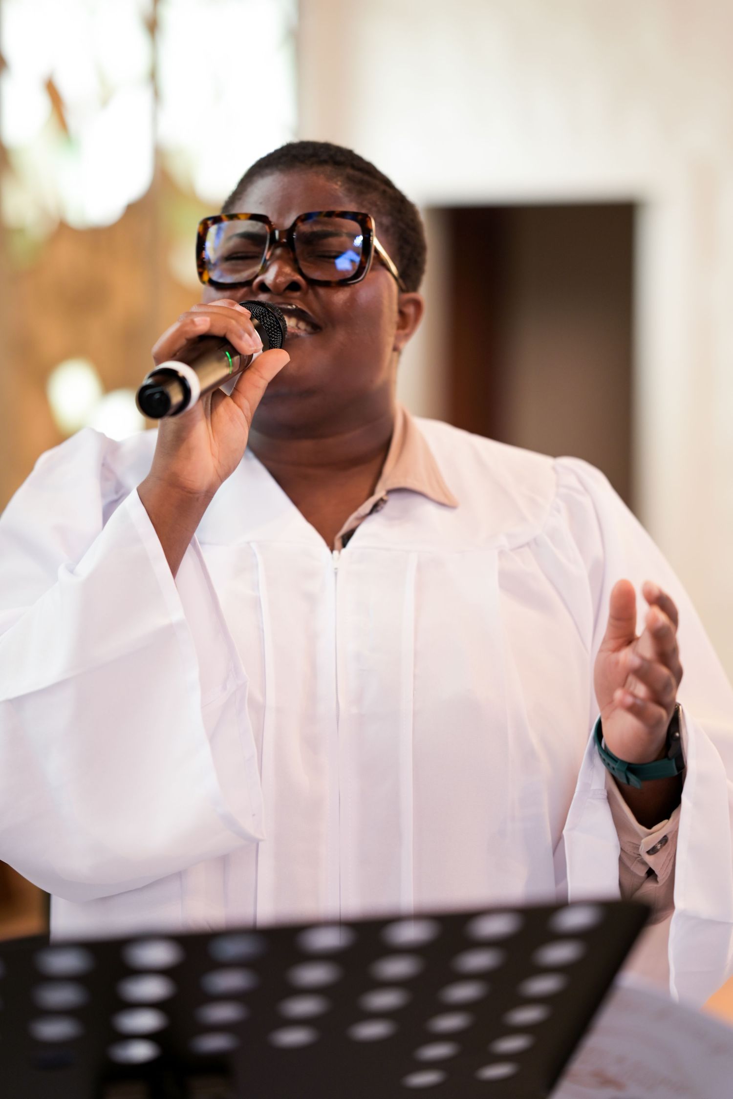 Church choir member in white robe singing during service.