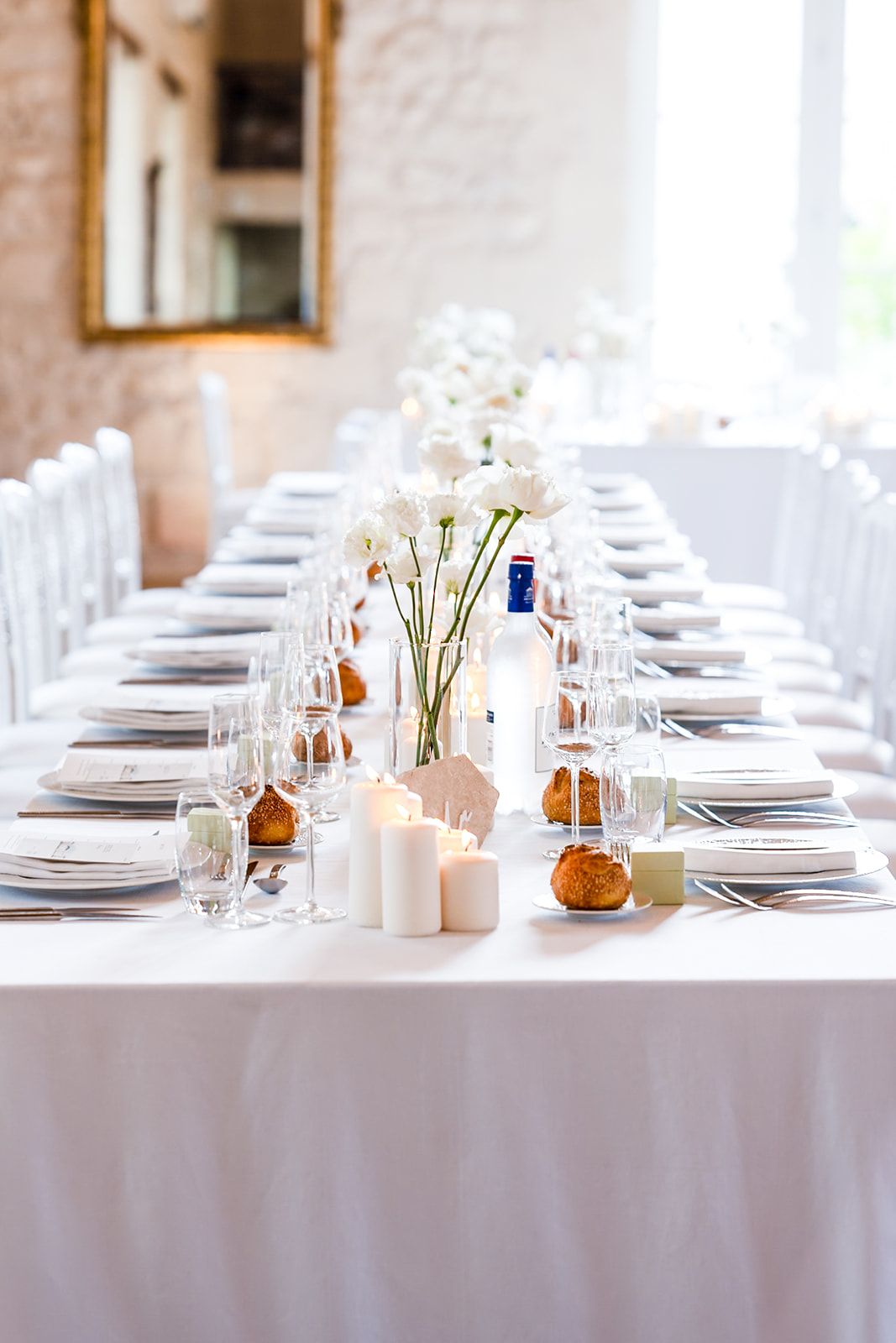 Elegant white wedding table setting with floral centerpieces, candles, and place settings.