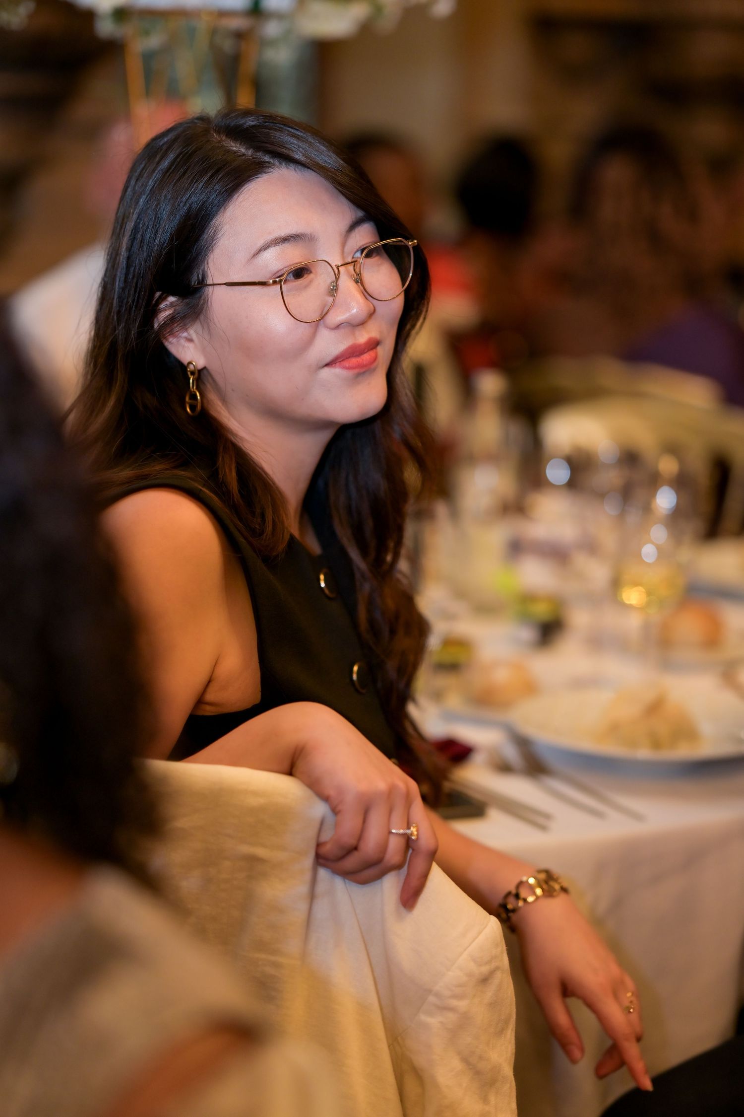 Guest in glasses smiling at elegant dinner reception.