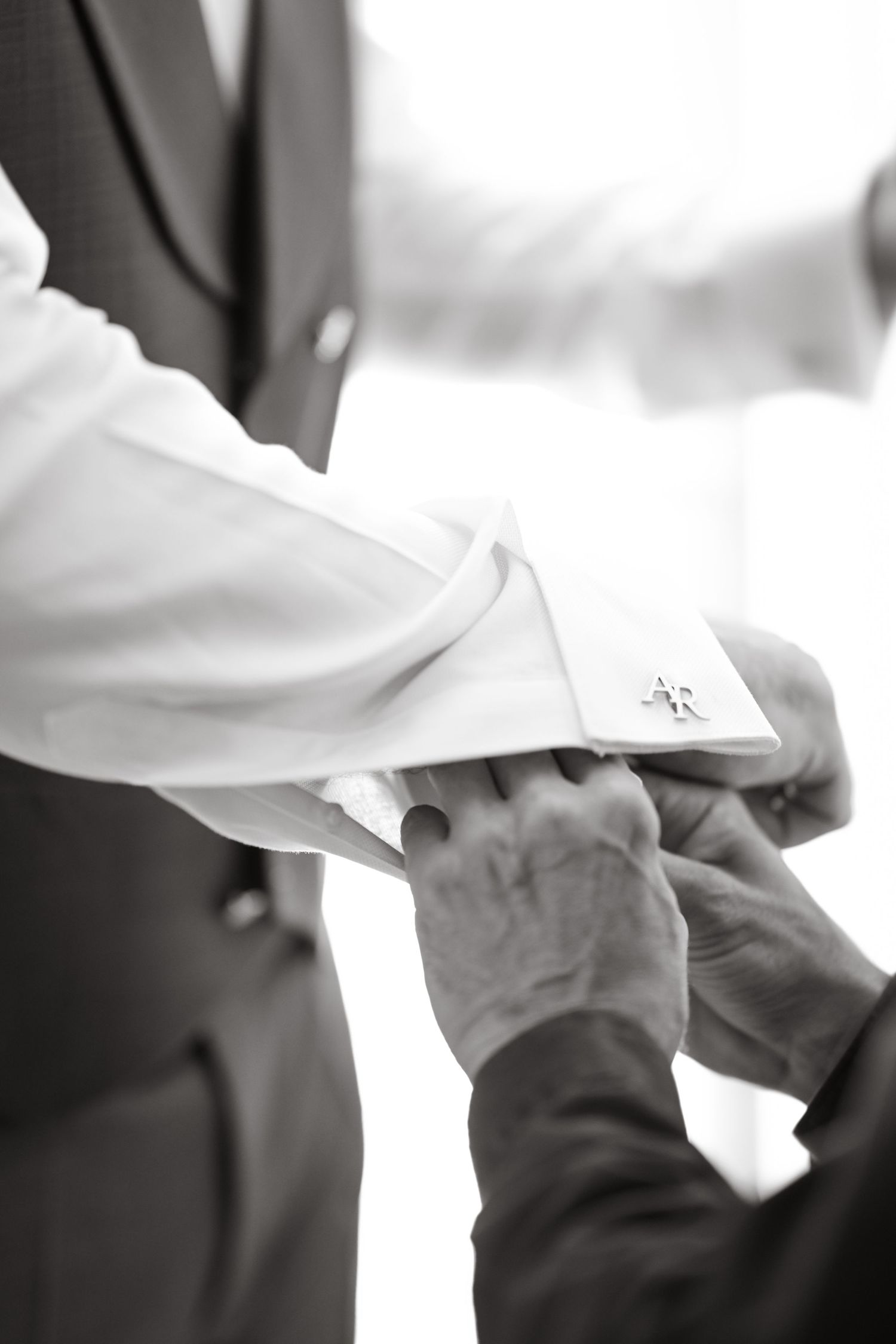 Close-up of white dress shirt cuffs being adjusted.
