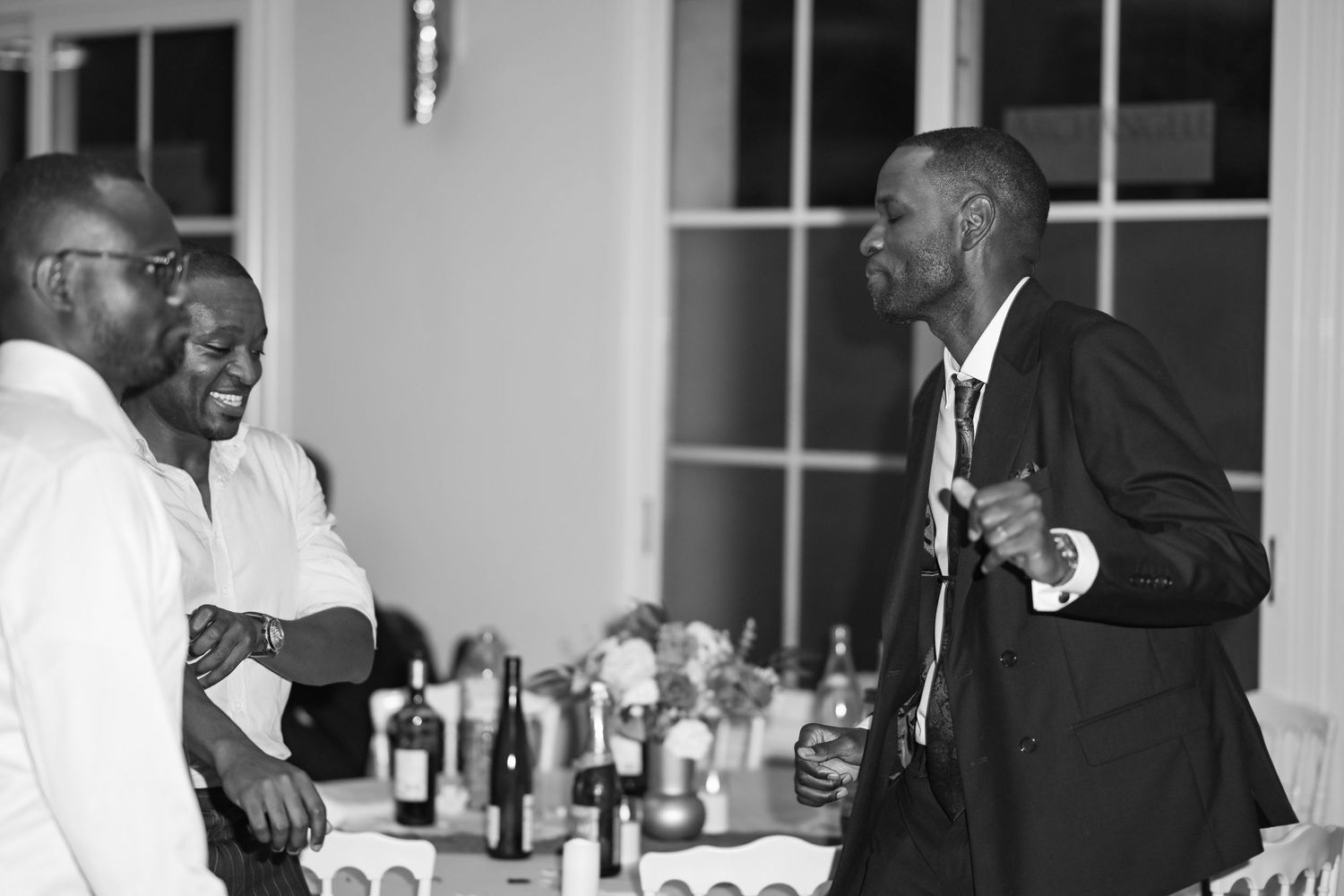 A candid black and white photo of guests engaged in lively conversation at an event.