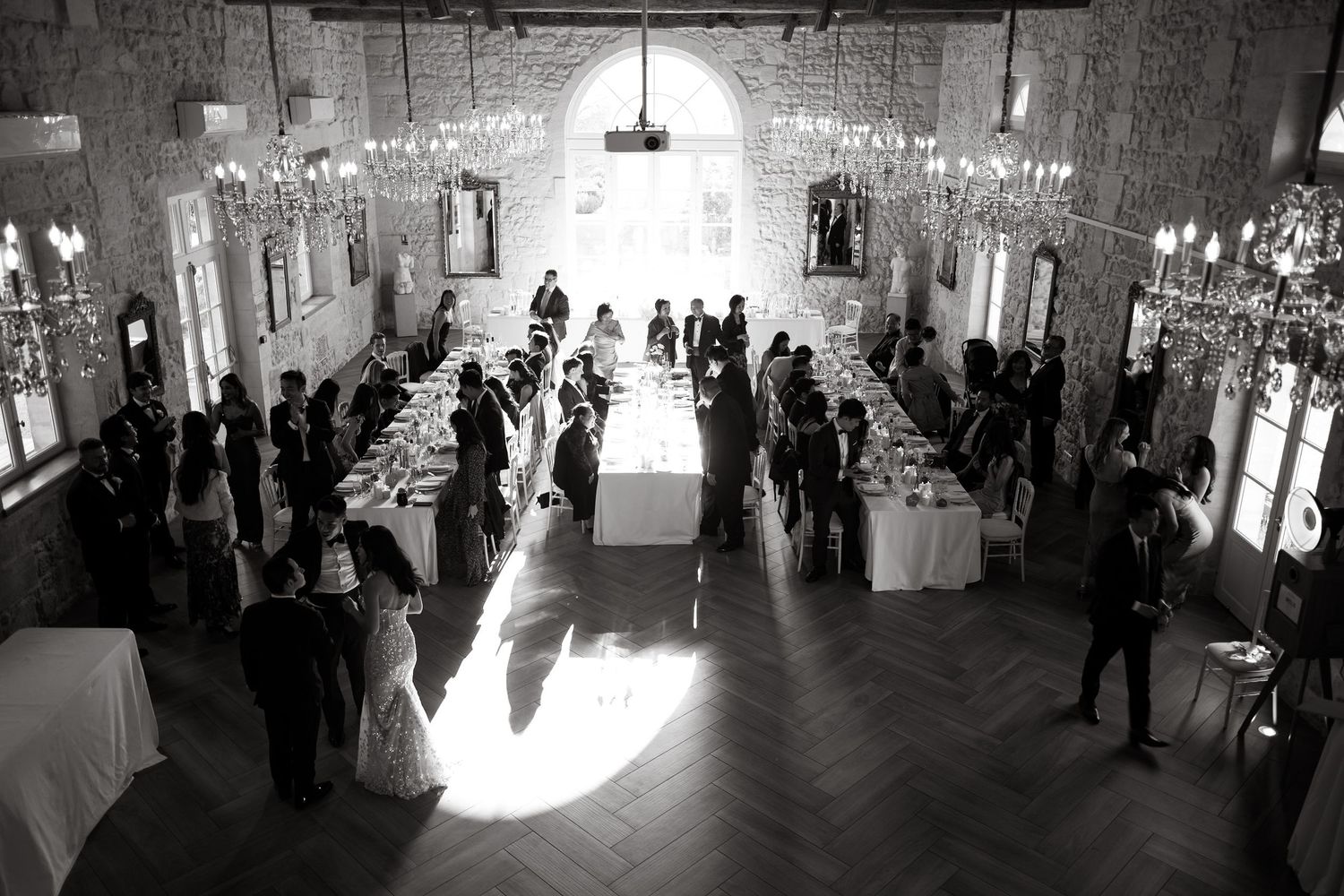 Elegant wedding reception venue with guests mingling around tables in a grand hall with dramatic lighting.