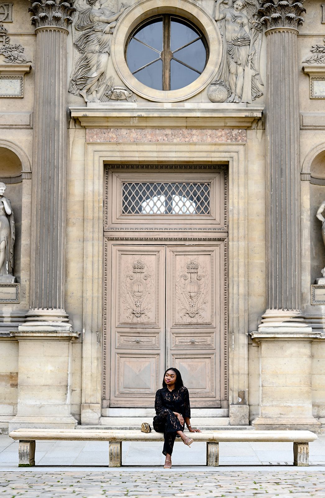 Classic architectural detail with round window, stone columns and ornate doorway.
