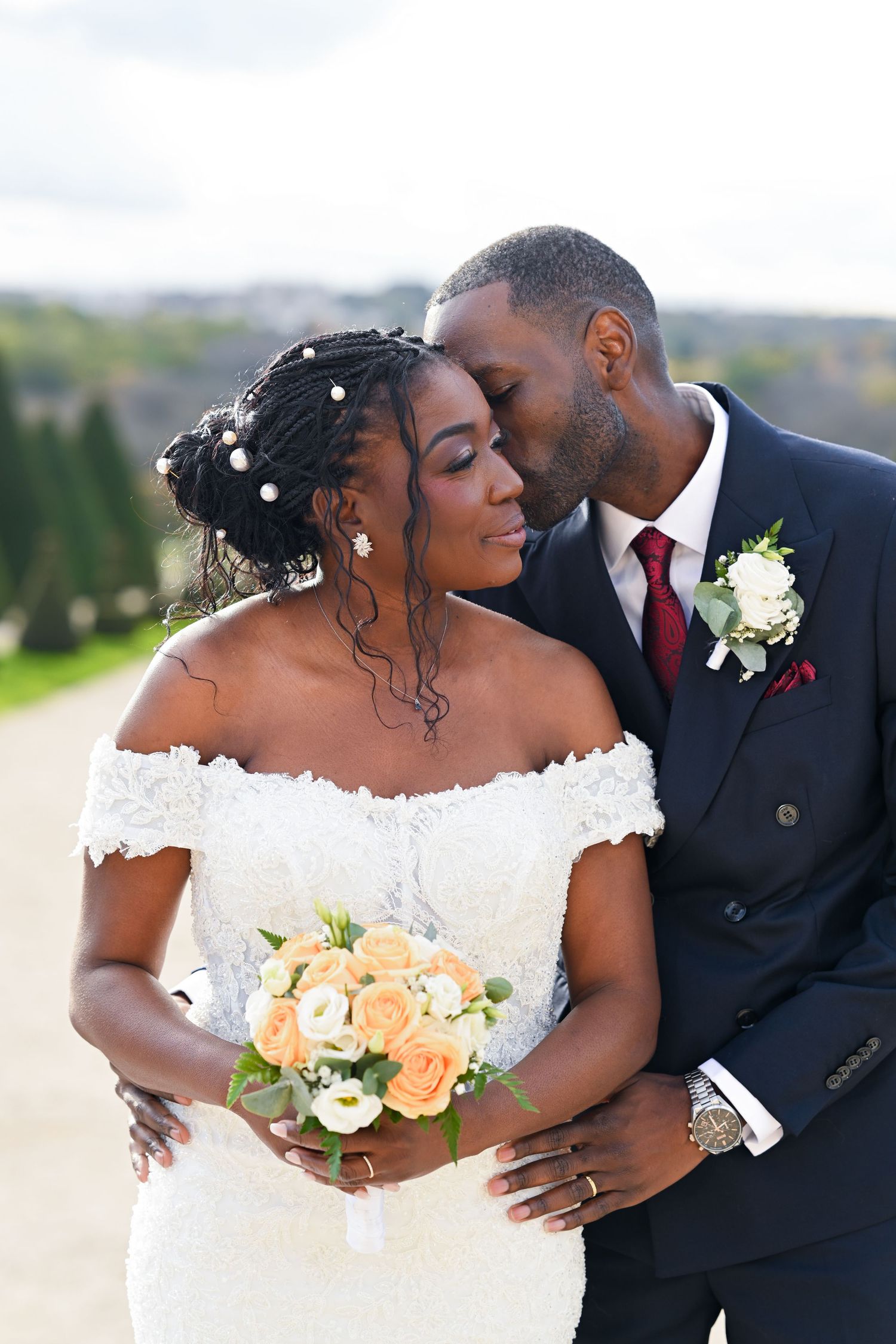 Intimate wedding portrait of couple sharing tender moment in elegant garden setting.