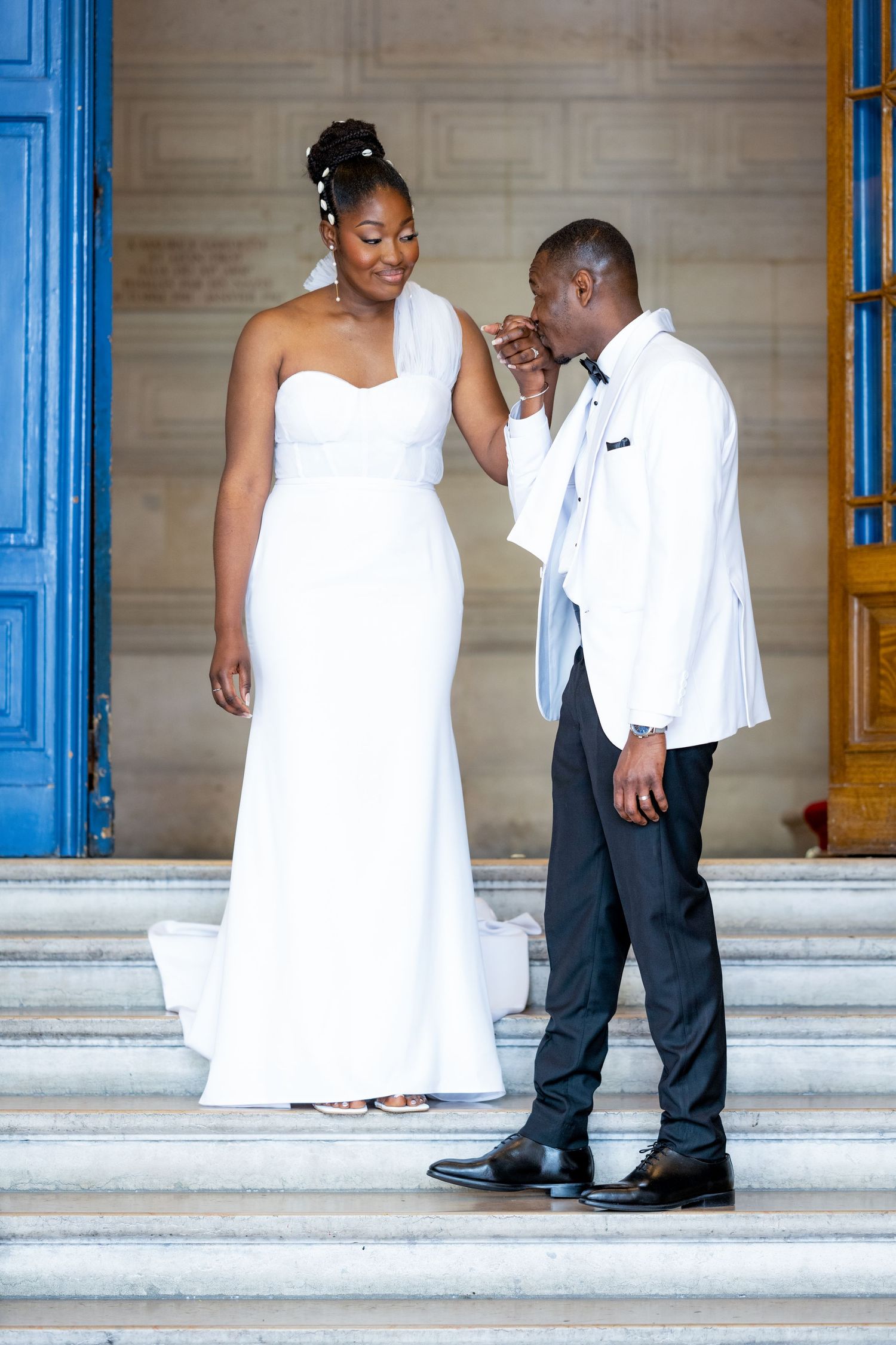 A couple shares intimate moments on marble steps during what appears to be a wedding photoshoot.