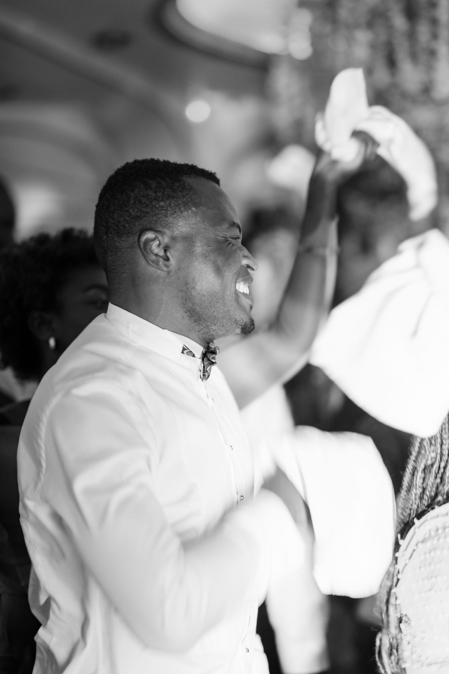 Guest in white shirt celebrating enthusiastically at formal event.