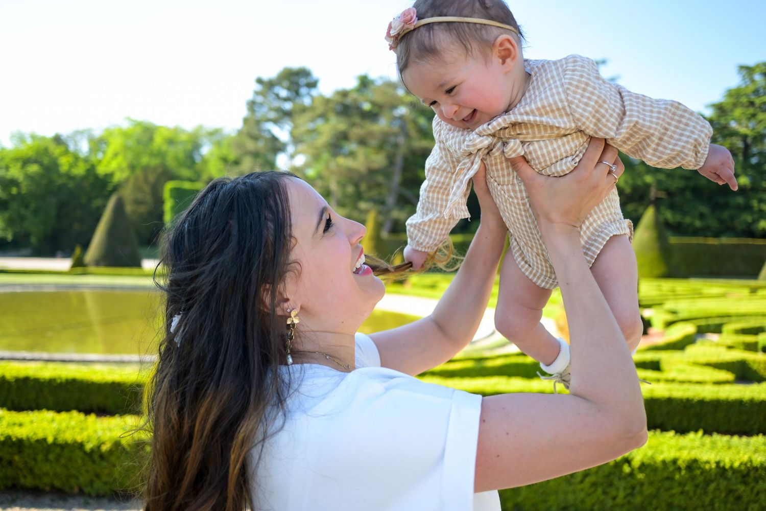 Family enjoying a playful moment together in a sunny garden setting.