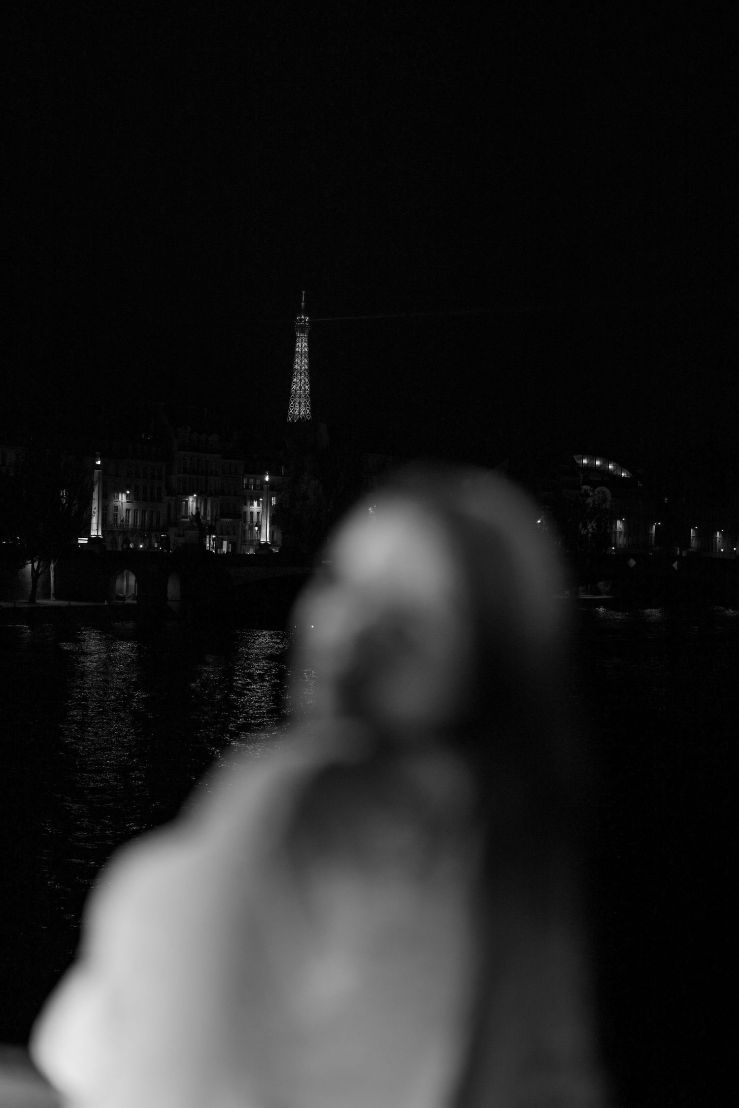 Night cityscape showing illuminated buildings and landmarks reflected on dark water.