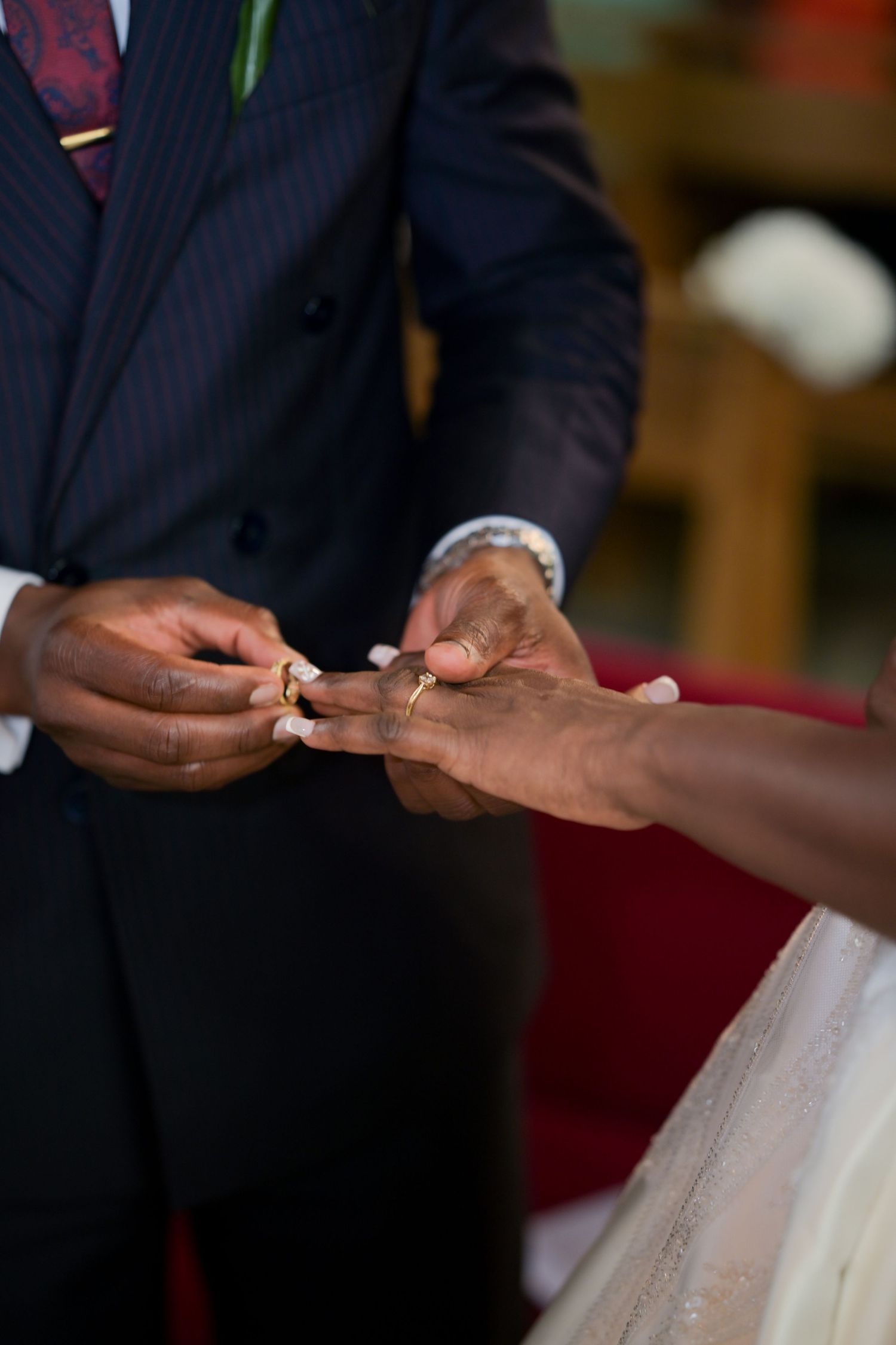 Close-up of hands exchanging wedding rings during ceremony.